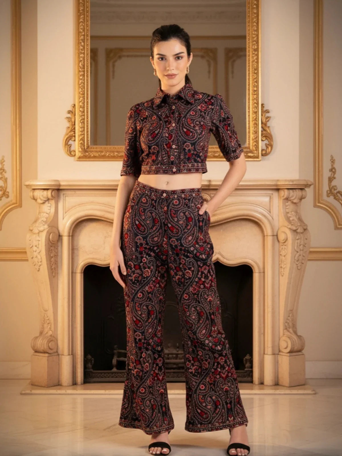 Woman wearing a Pretty Pixie luxury paisley co-ord set with crop shirt and wide-leg pants, styled indoors in an elegant room for a modern ethnic fashion look.