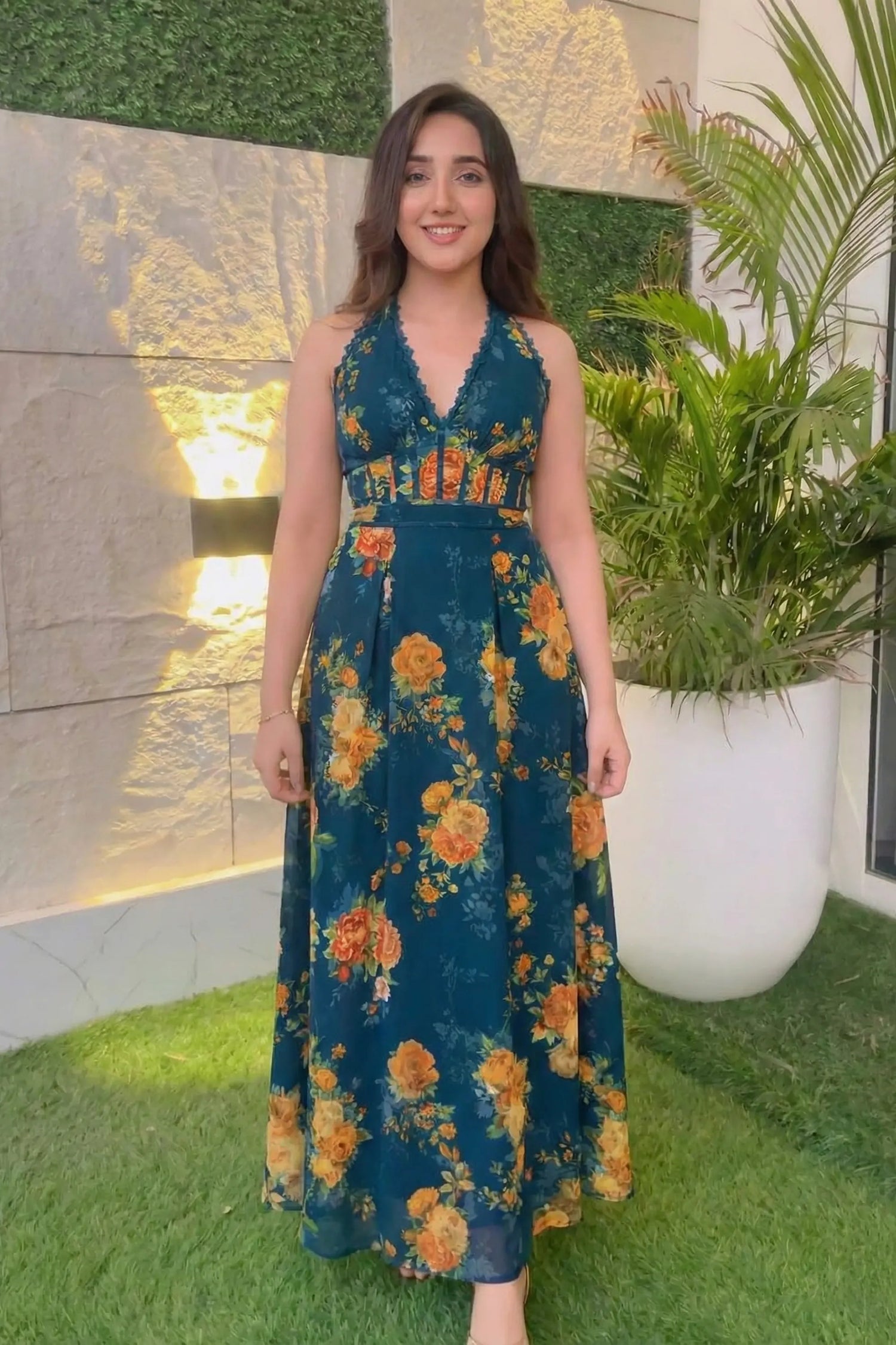 Woman wearing navy blue floral maxi dress standing in garden courtyard, Ashnoor Kaur inspired look India 2025.