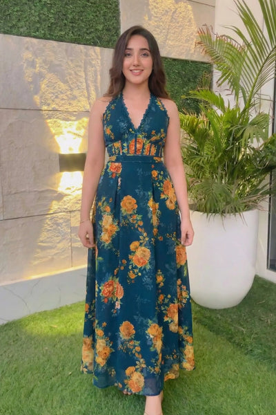 Woman wearing navy blue floral maxi dress standing in garden courtyard, Ashnoor Kaur inspired look India 2025.