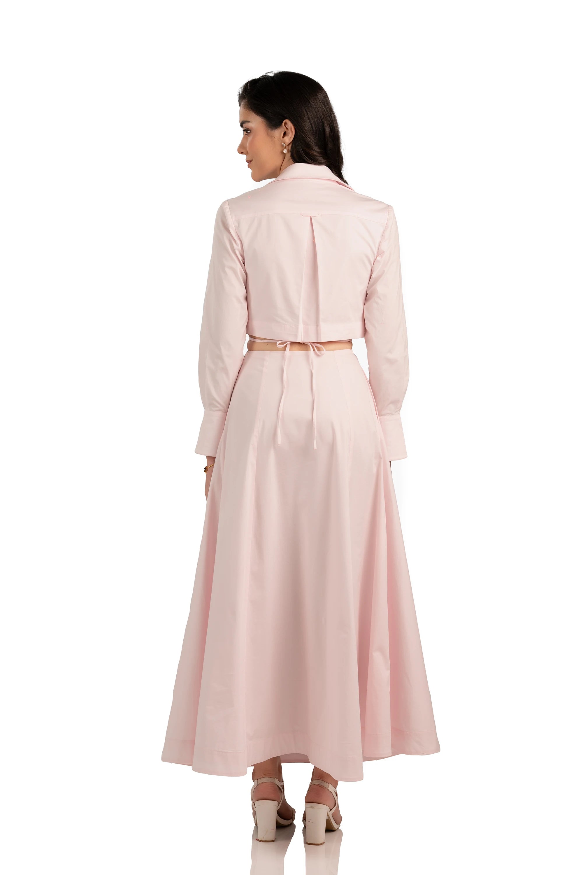Back view of light pink maxi dress featuring long sleeves, A-line skirt, and adjustable tie-back waist.