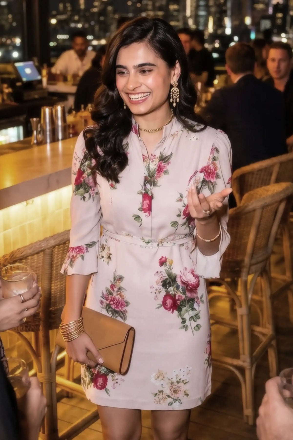 Woman smiling at a rooftop bar wearing Pretty Pixie's beige garden rose puff-sleeve belted mini dress