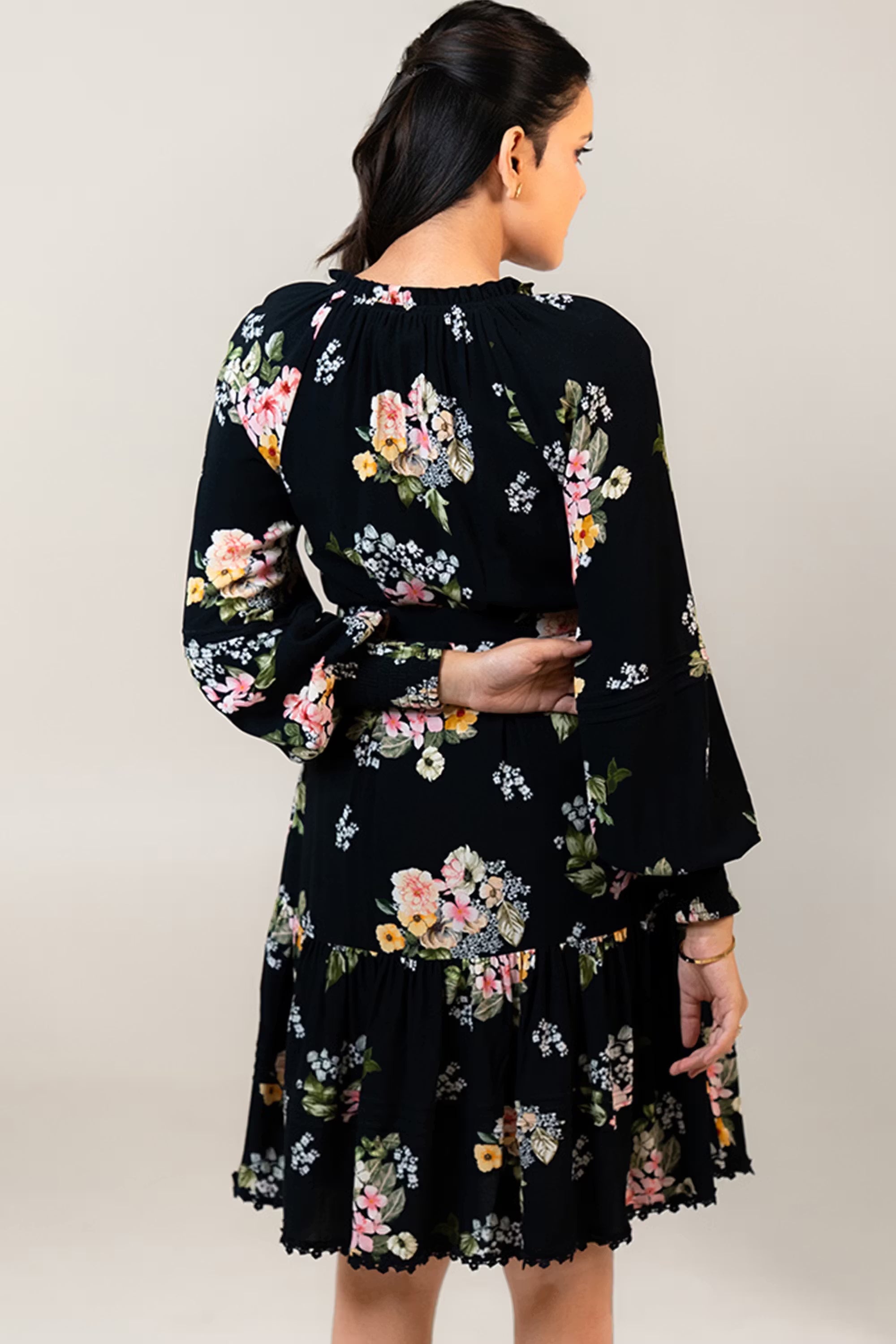 Back view of black floral belted short dress with tiered skirt and floral print pattern