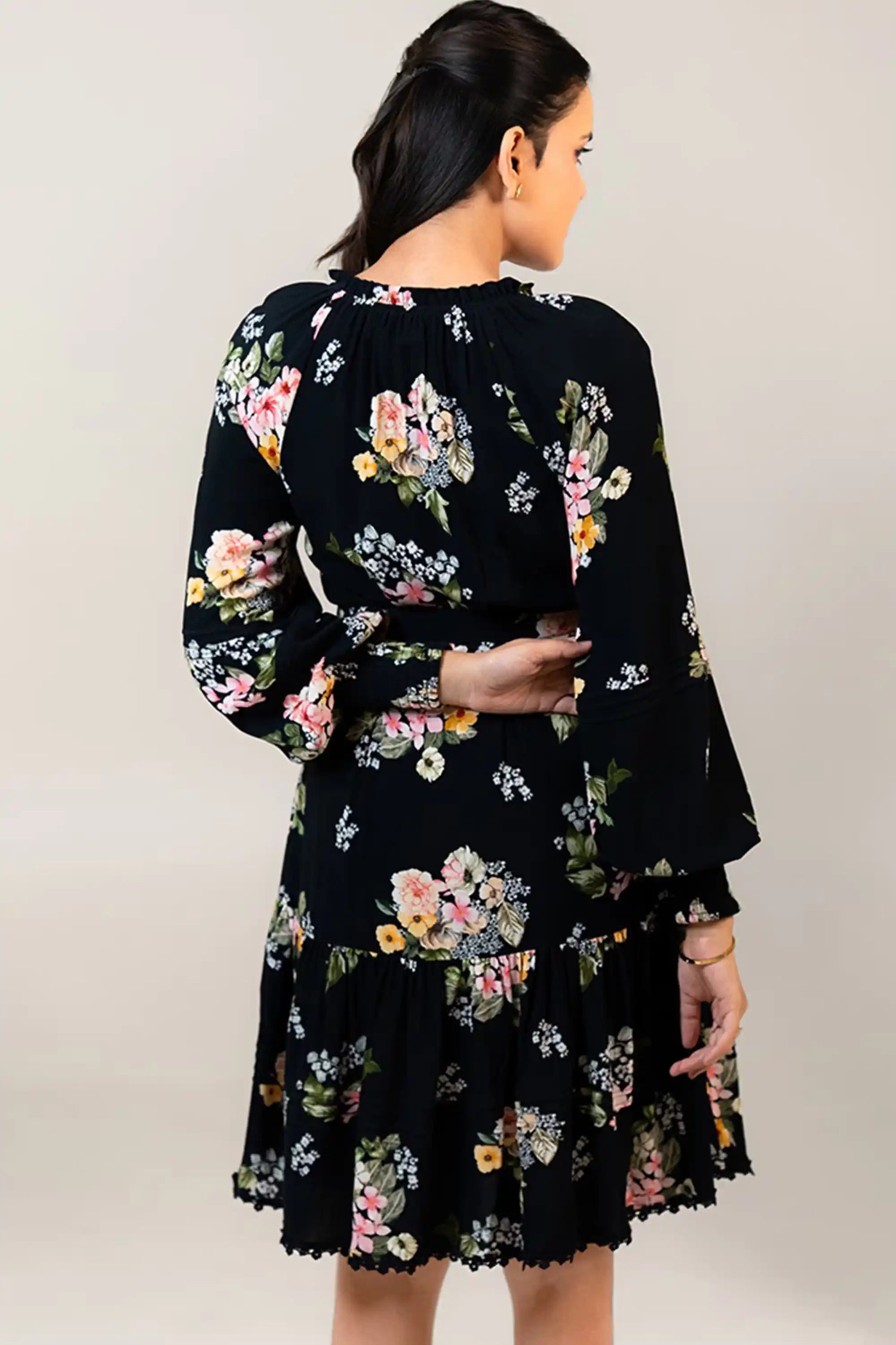 Back view of black floral belted mini dress with fitted waistline.