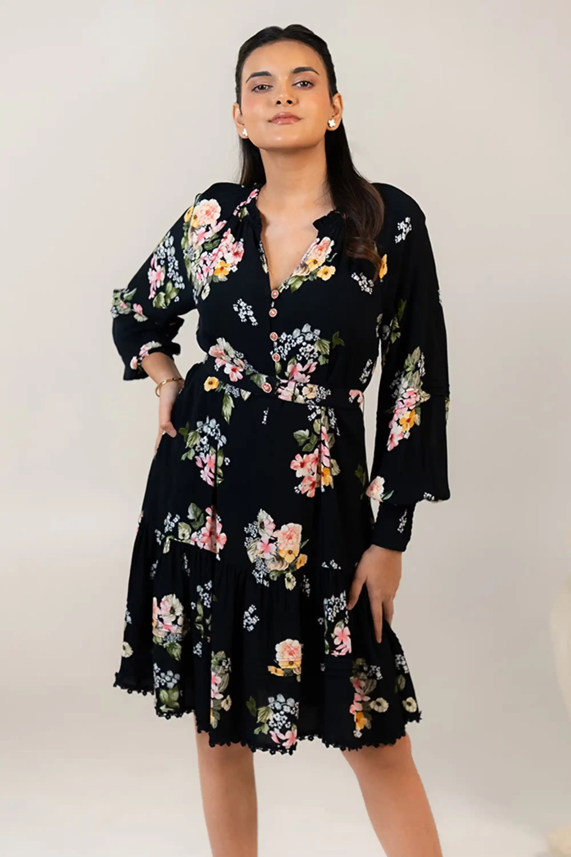 Closeup of black floral mini dress showing colorful floral pattern and waist belt.