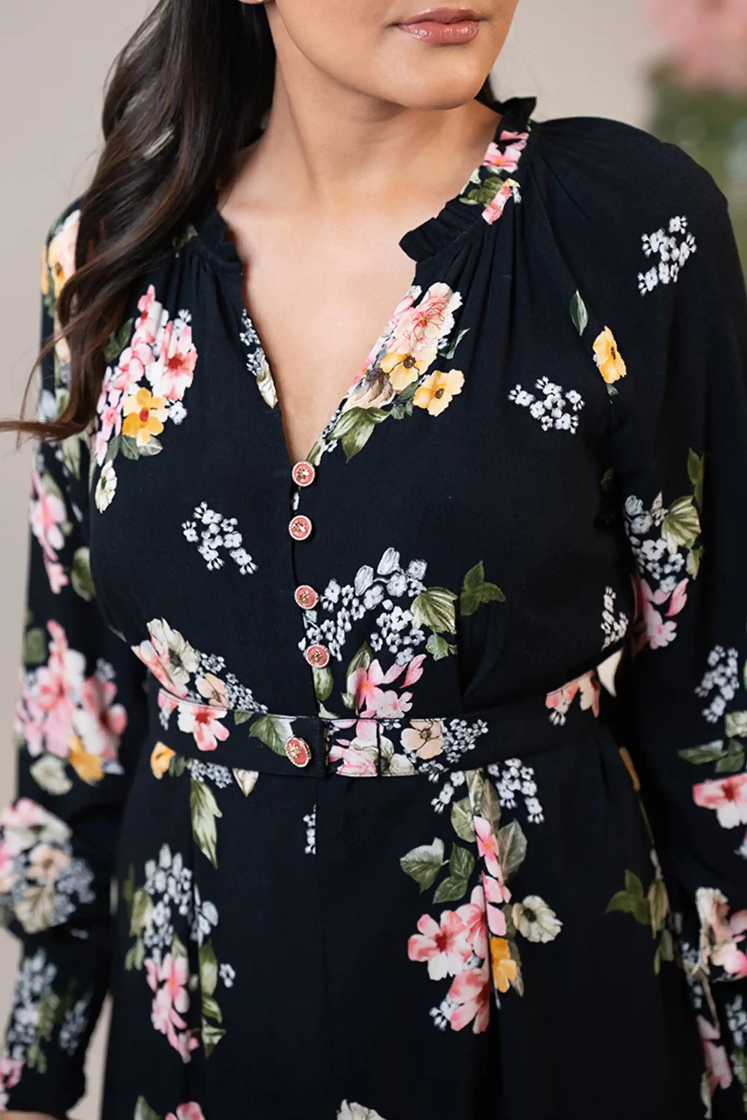 Neckline detail of black floral belted mini dress with button accents.