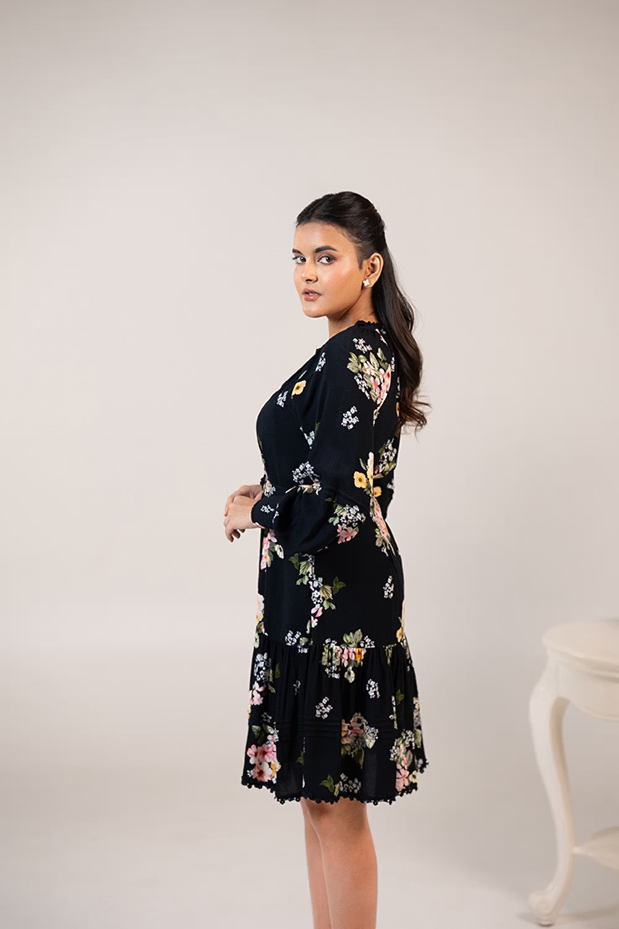 Side profile of black floral short dress with flared hem and belted waist design