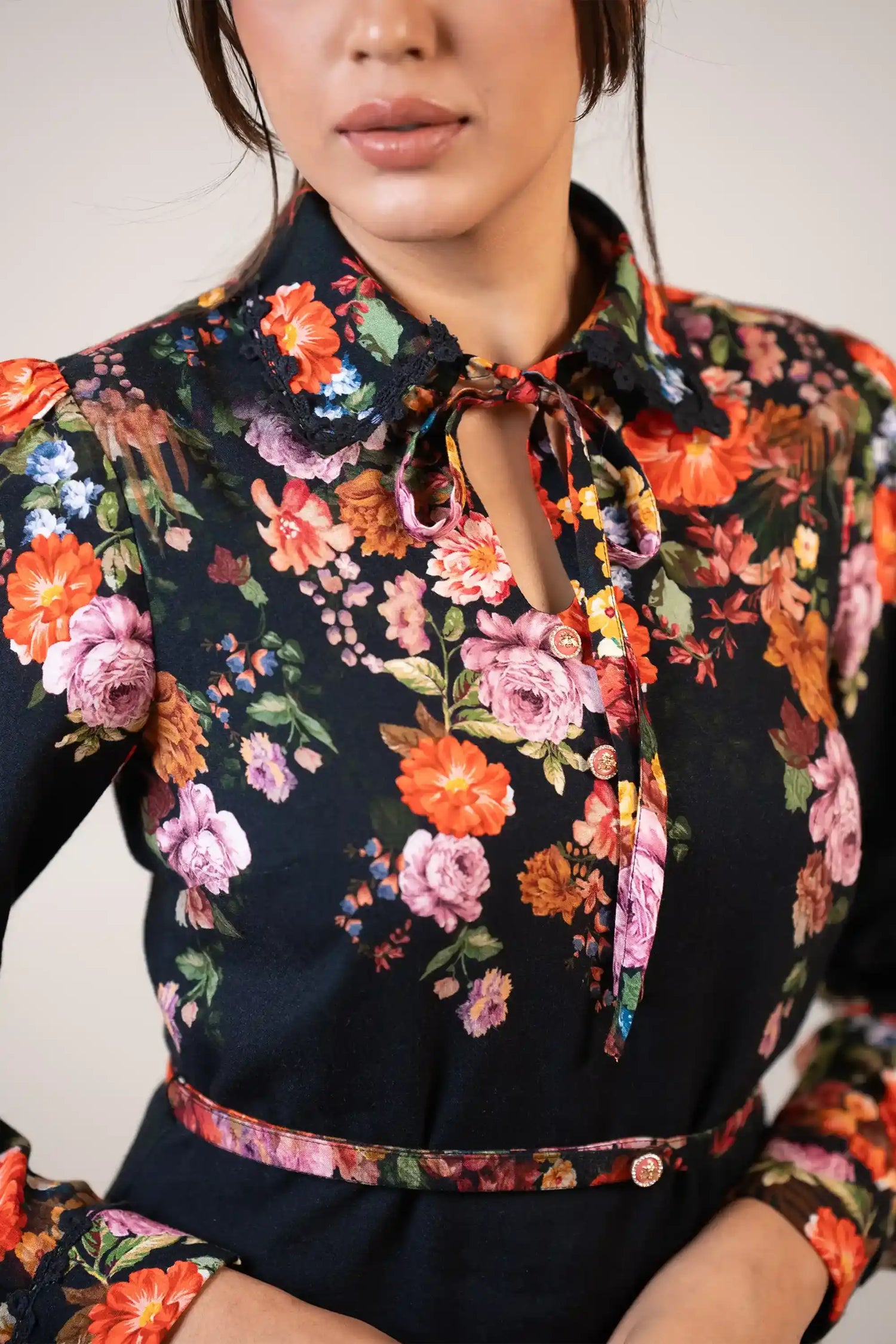 Closeup of bow-tie neckline and collar detail on black floral dress with bright multicolor prints