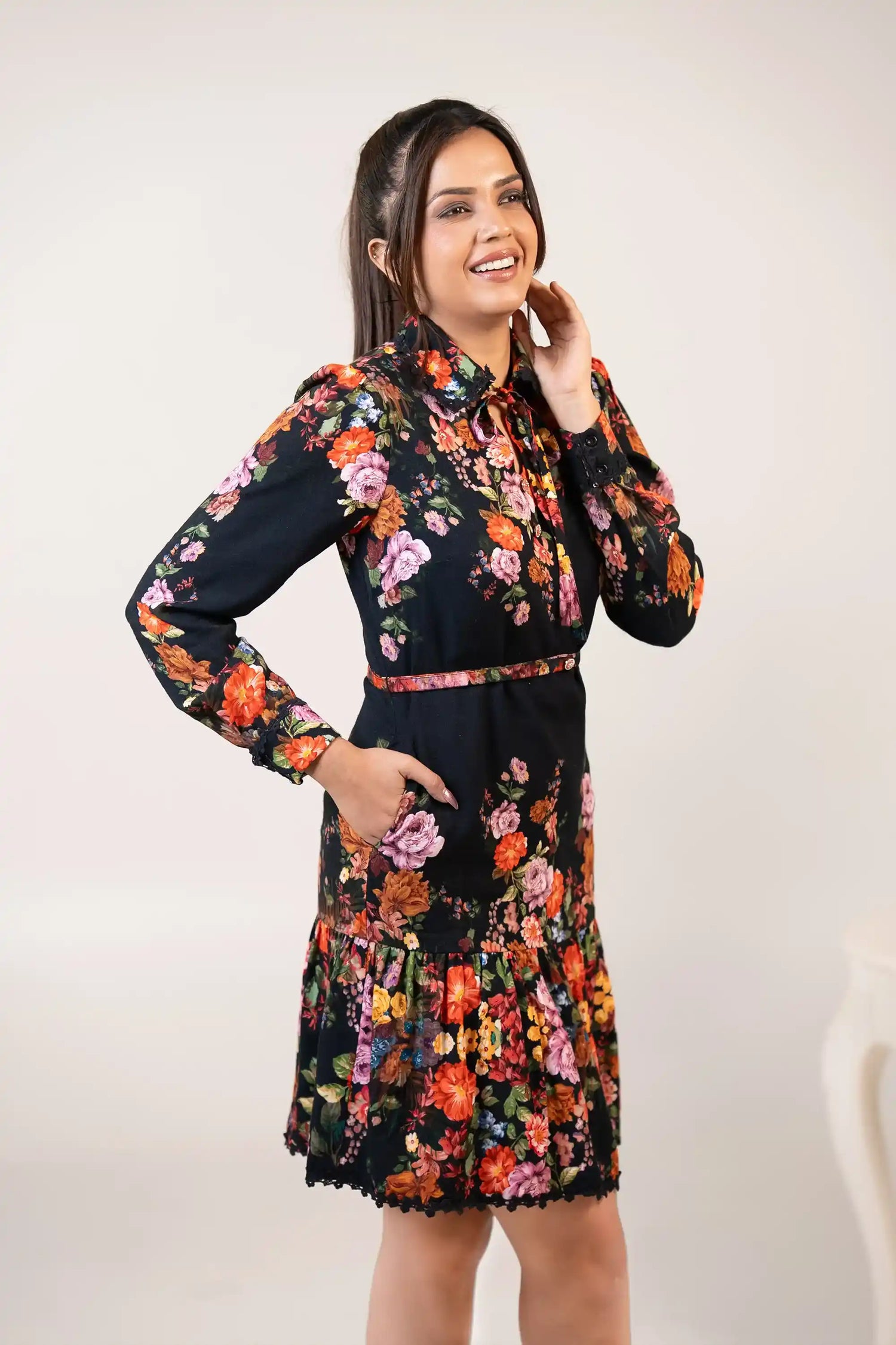 Side view of black floral bow-tie collar dress with waist belt, long sleeves, and vibrant print