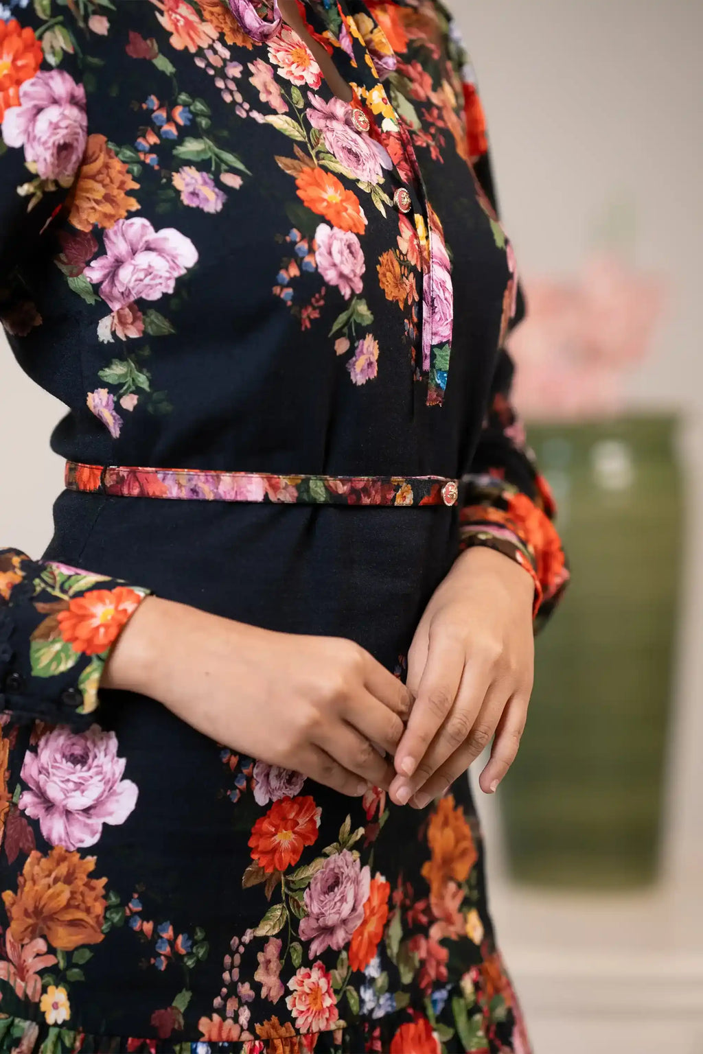 Waist belt detail of black floral bow-tie dress with button accents and multicolor floral pattern