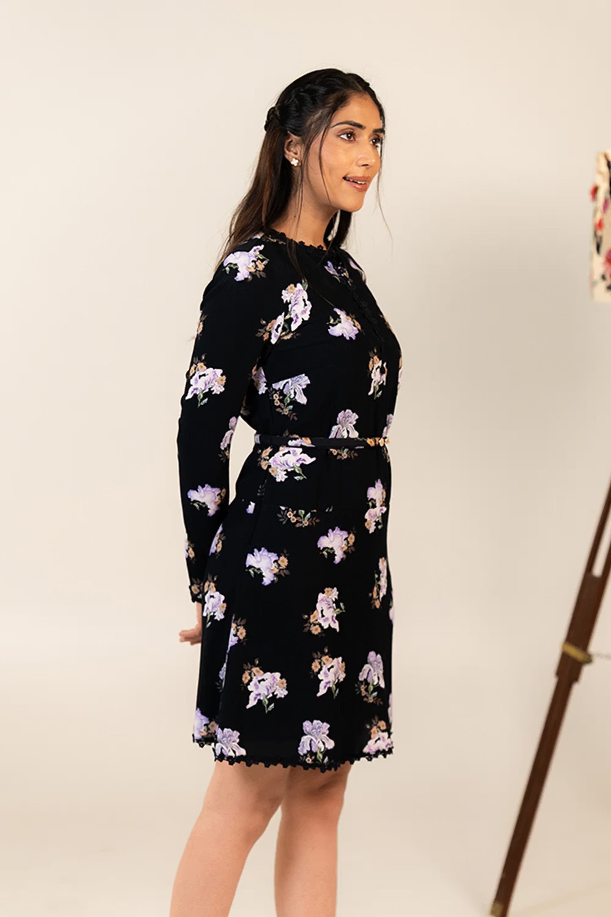Side profile of black floral mini dress with lilac flower print and fitted waist belt