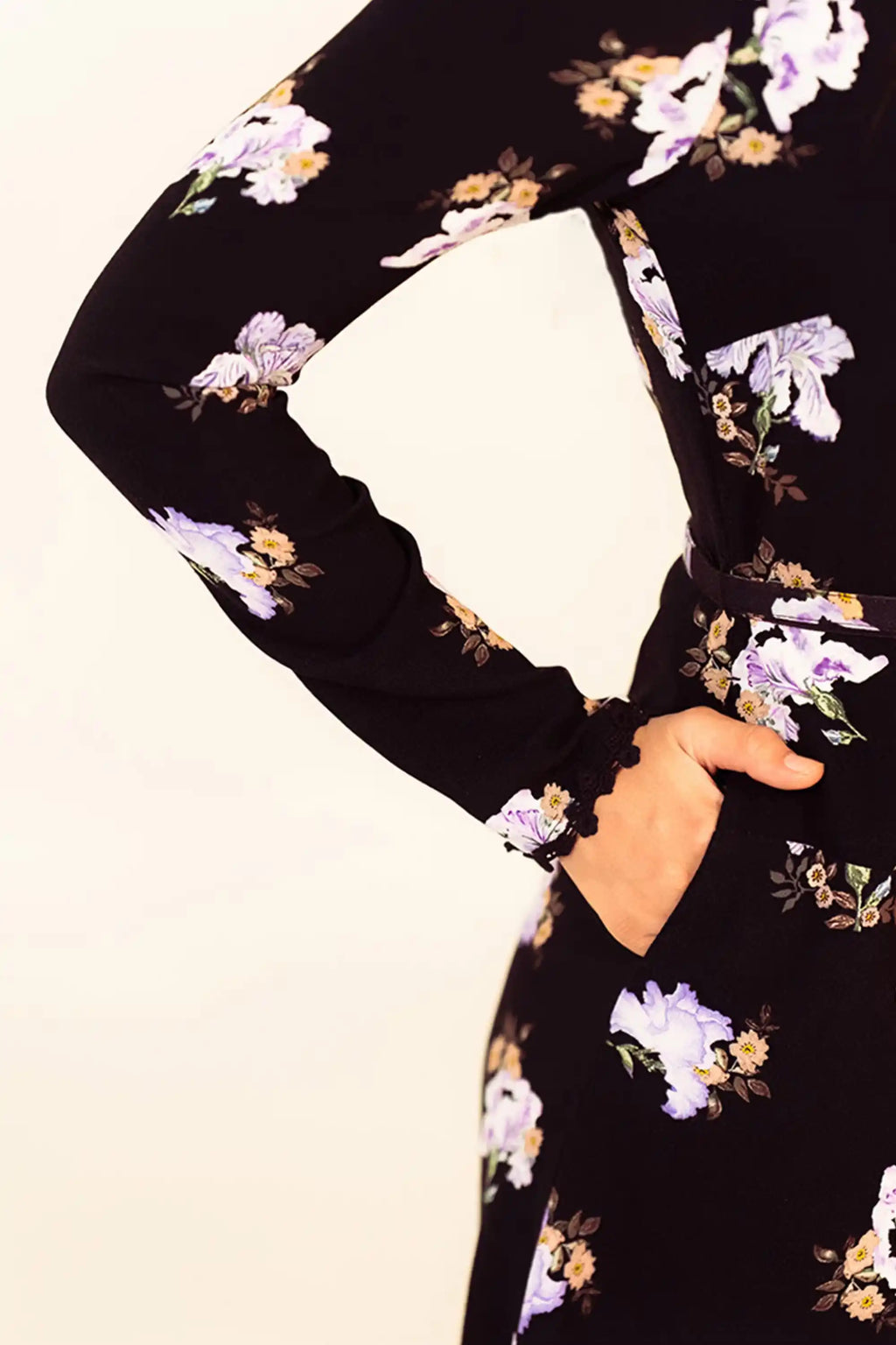 Closeup of sleeve and pocket detail on black floral mini dress with lilac prints