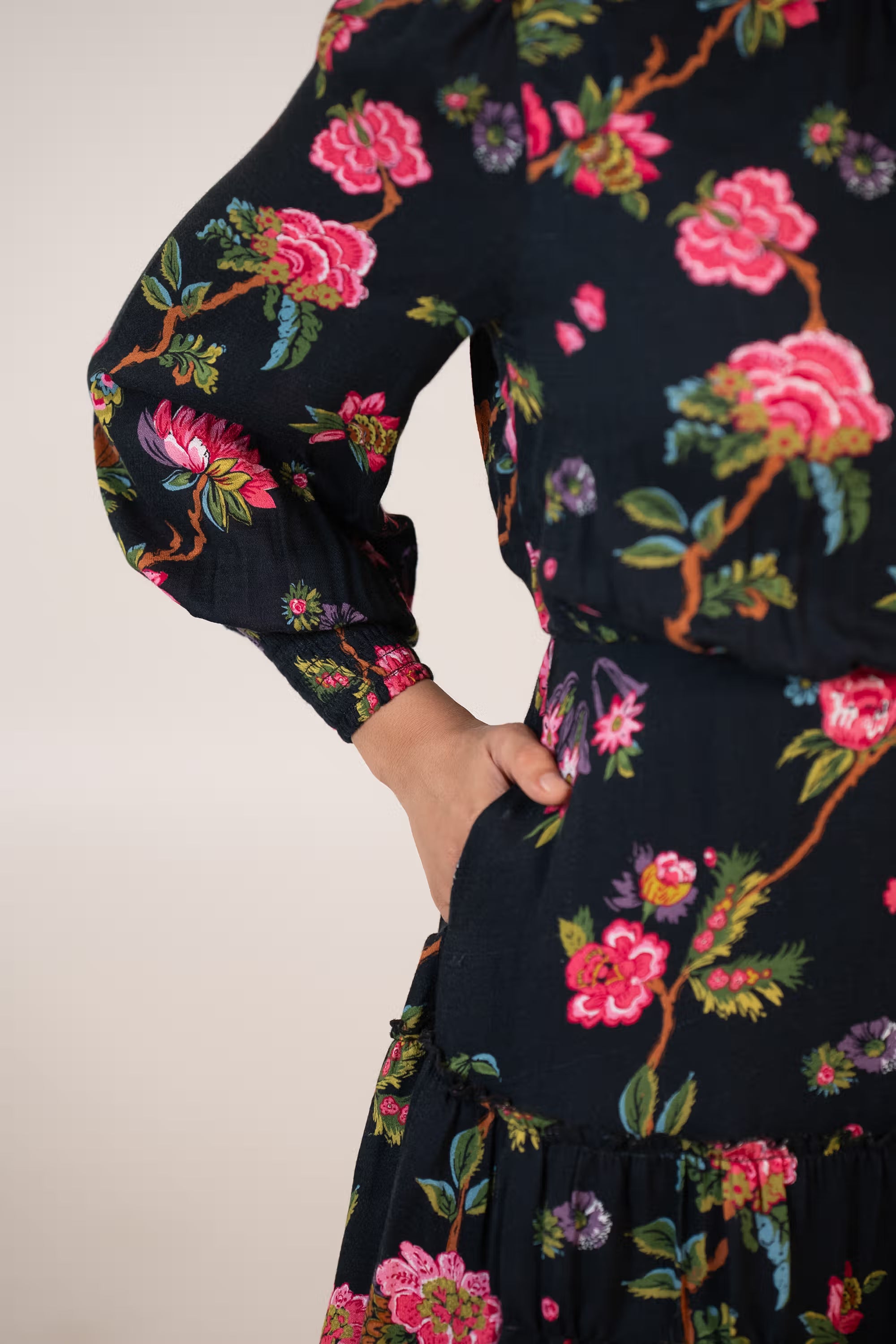 Sleeve detail of black floral mini dress with puffed long sleeves and pink lace edge.
