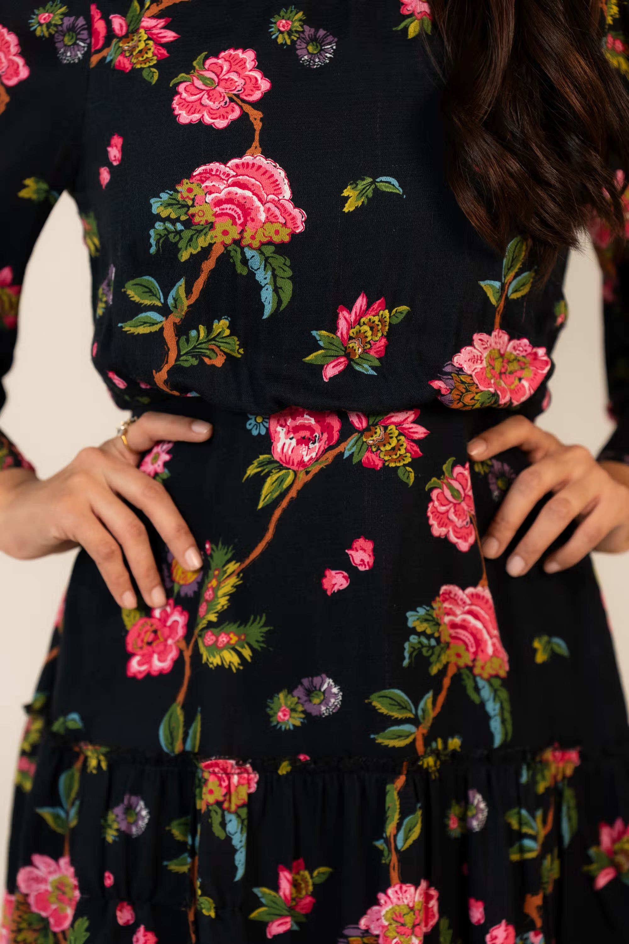 Closeup of floral detailing on black mini dress with pink flower prints and lace trim.