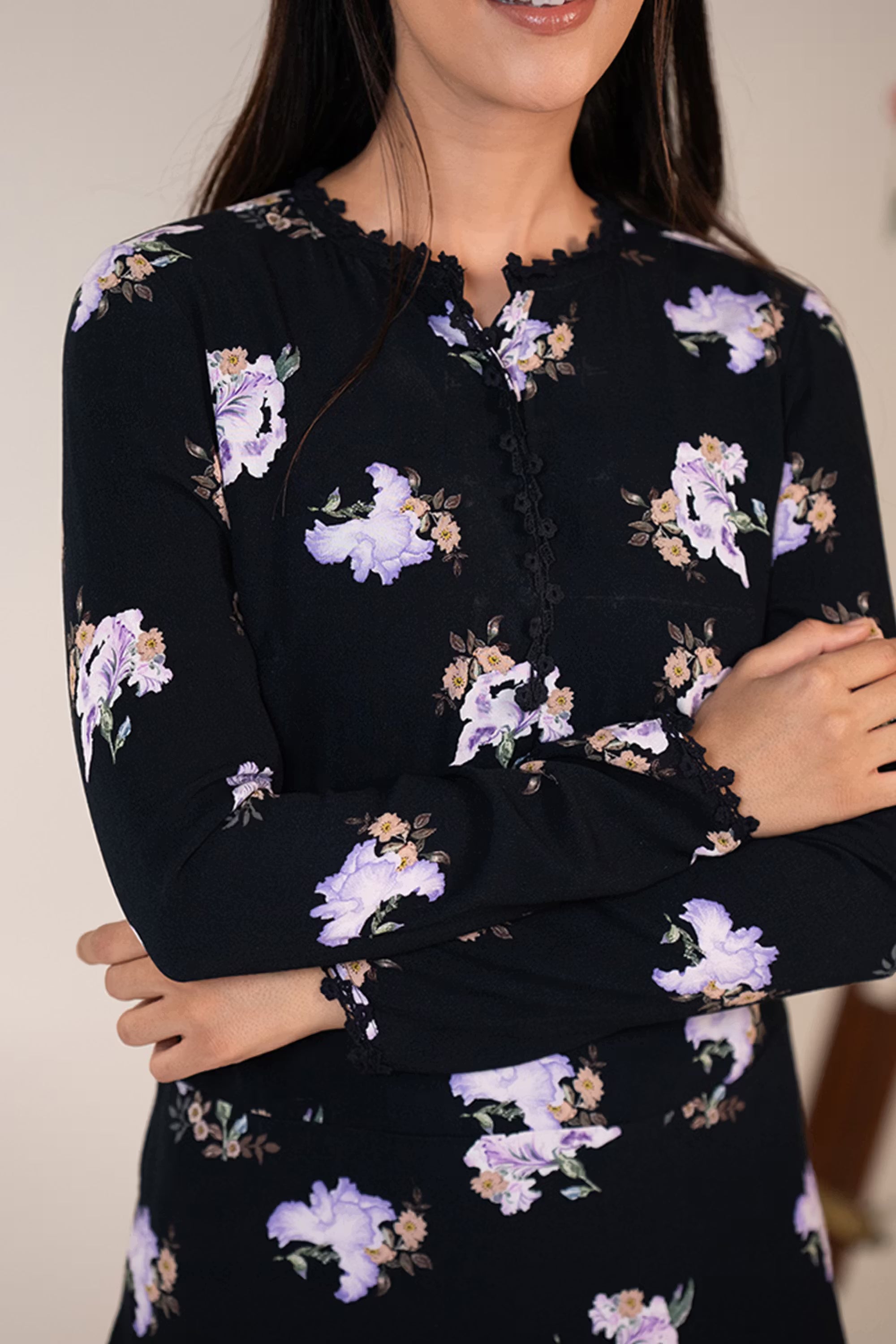 Closeup of black floral dress with lilac flower print, button detail, and scalloped neckline