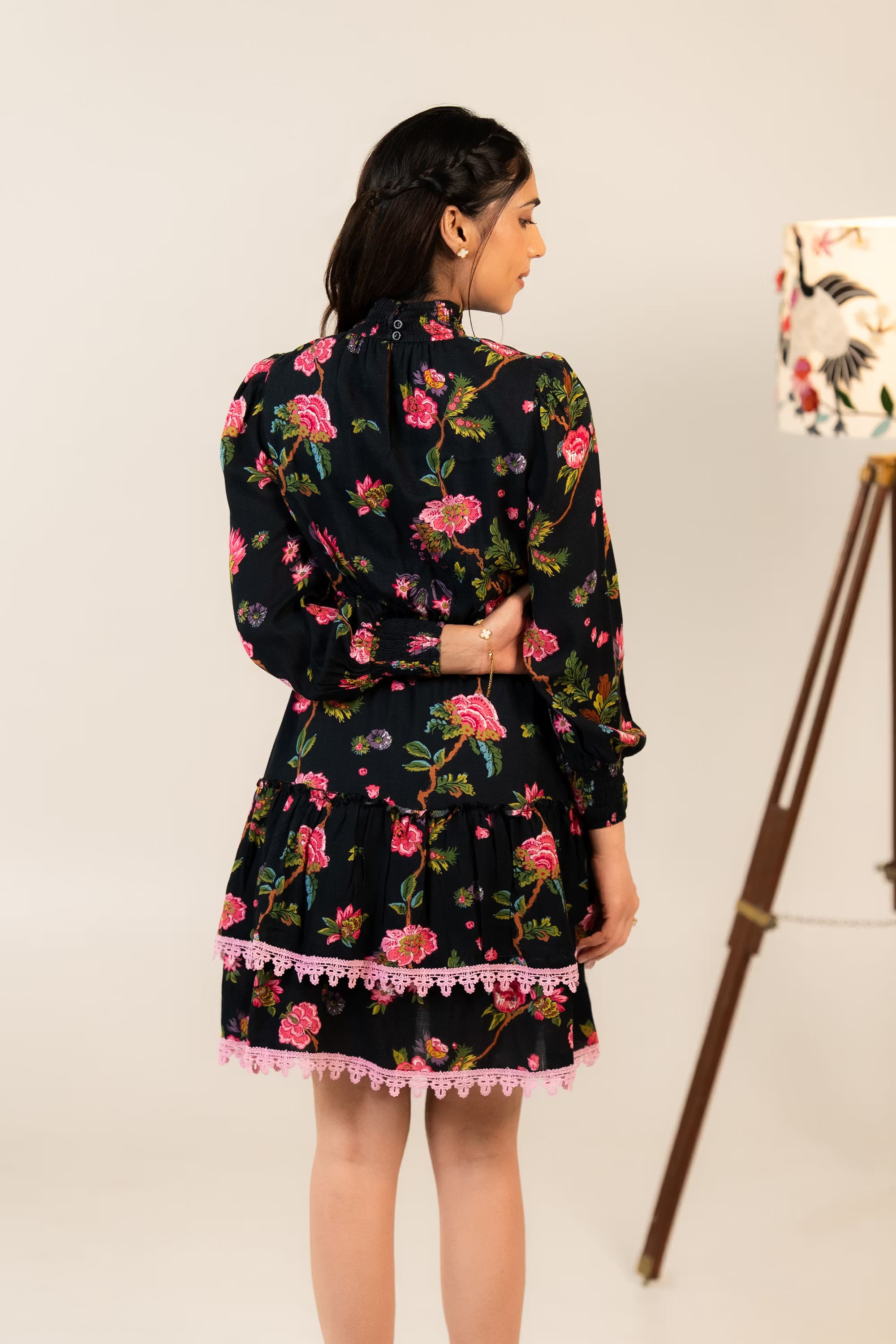 Back view of black floral mini dress with pink lace hemline and floral.