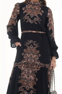 Woman in Pretty Pixie black paisley high-neck tiered belted maxi dress