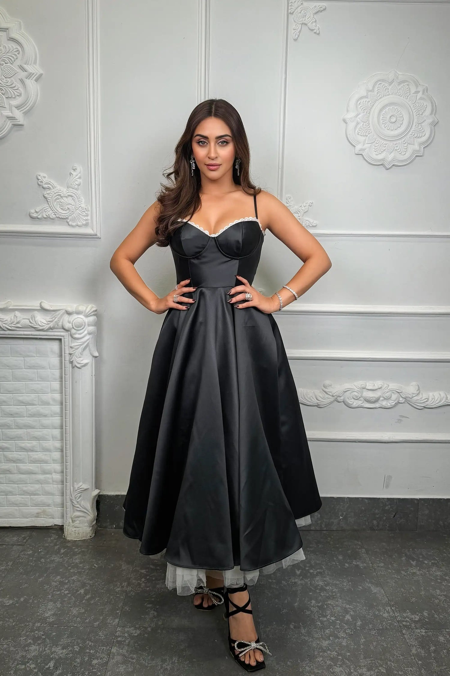 Krystle D'Souza wearing a black satin corset midi dress with lace trim and a flared skirt, styled for an elegant evening or party look by Pretty Pixie.