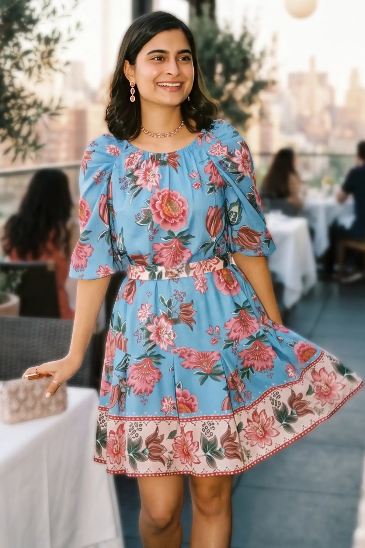 Woman twirling at a rooftop restaurant wearing Pretty Pixie's blue floral puff-sleeve belted mini dress