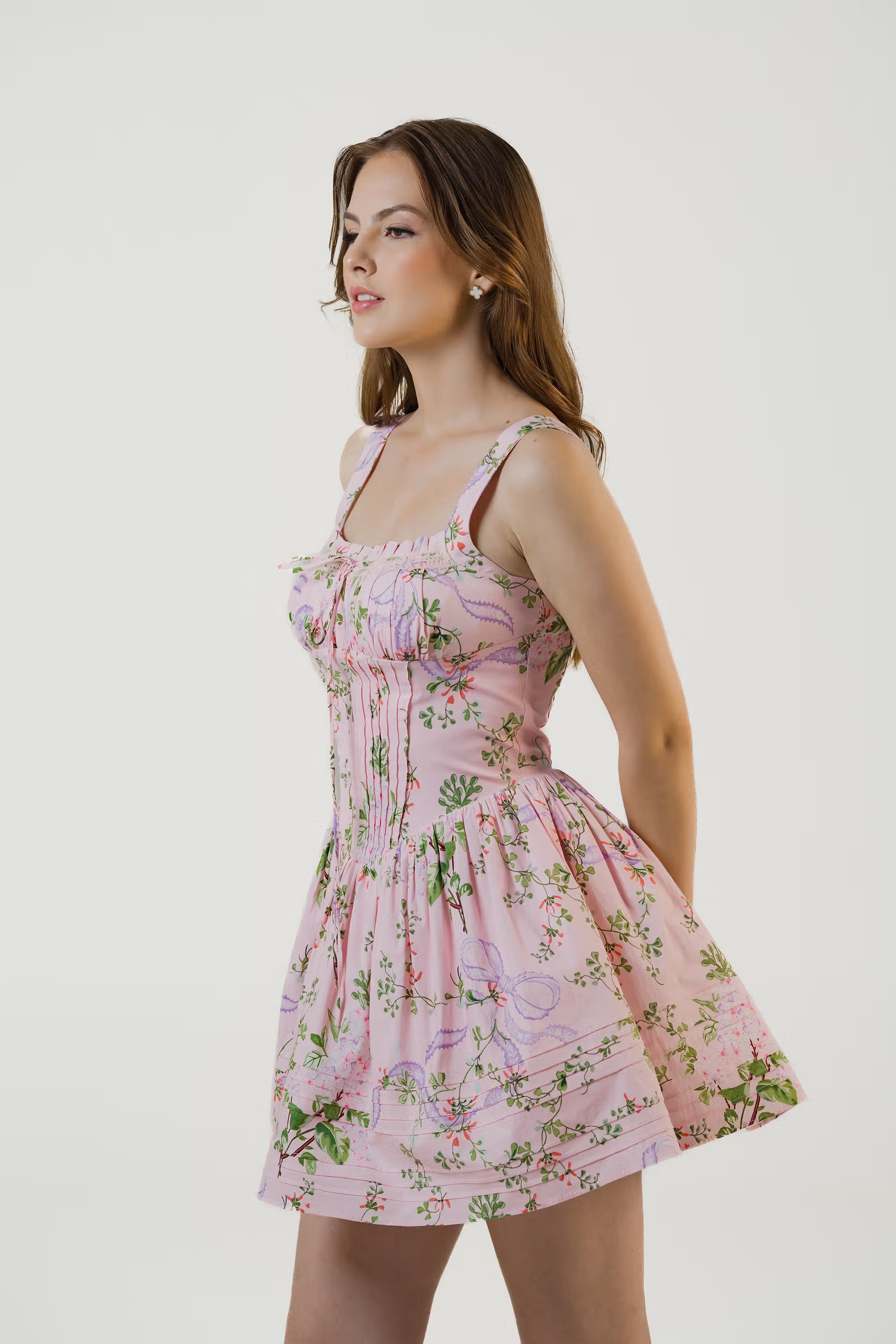 Side profile of blush pink corset style floral mini dress with fitted waist and flared skirt