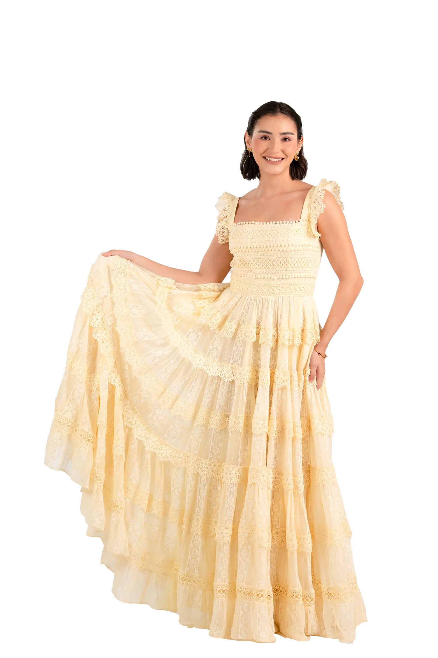 Model lifts skirt of buttercream lace tiered maxi dress to show volume and lace.