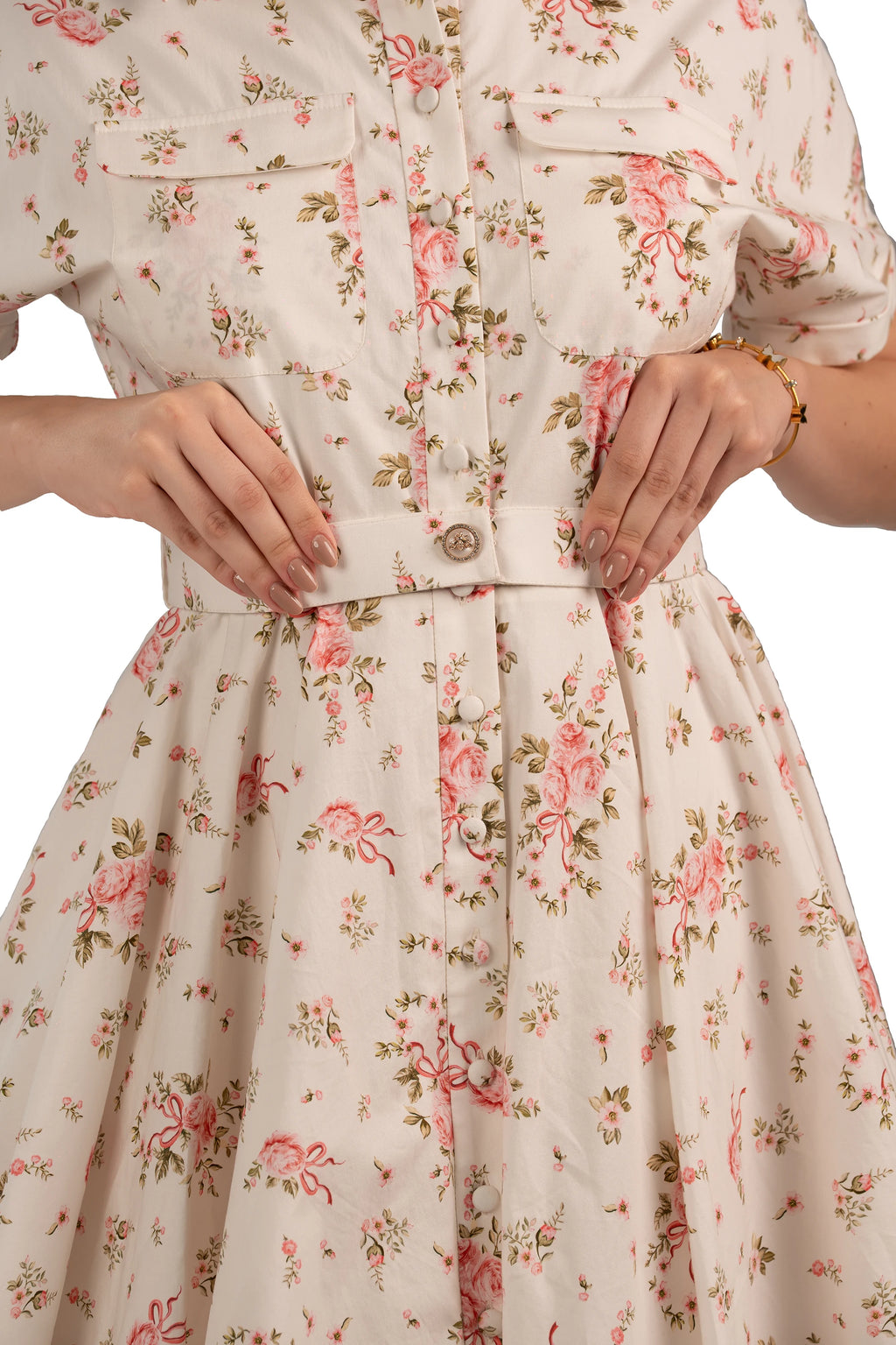 Close-up of belted button-down floral dress with front pockets and pink rose pattern, detail shot.