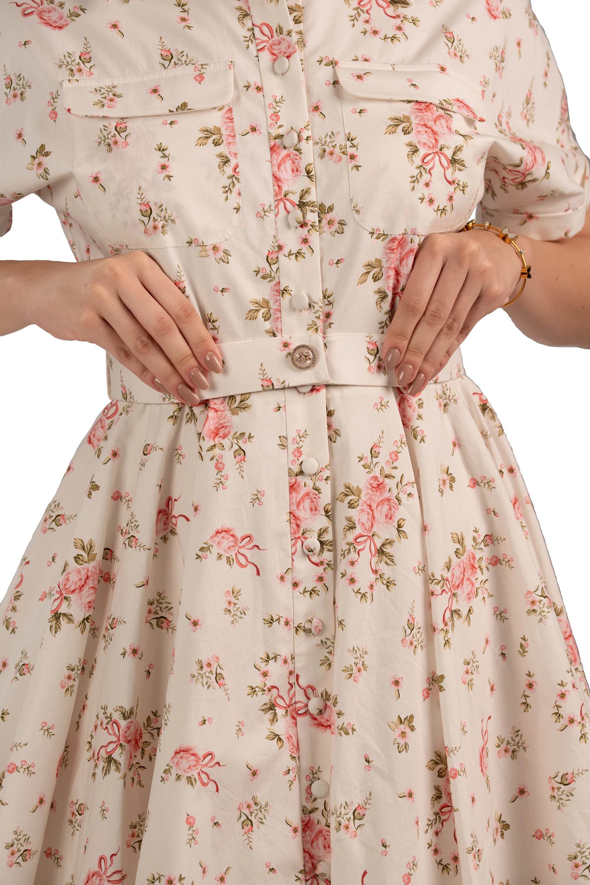 Close-up of belted button-down floral dress with front pockets and pink rose pattern, detail shot.