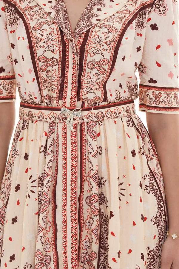 Close-up of Pretty Pixie cream bandana-print collared belted dress with crystal bow brooch waist detail