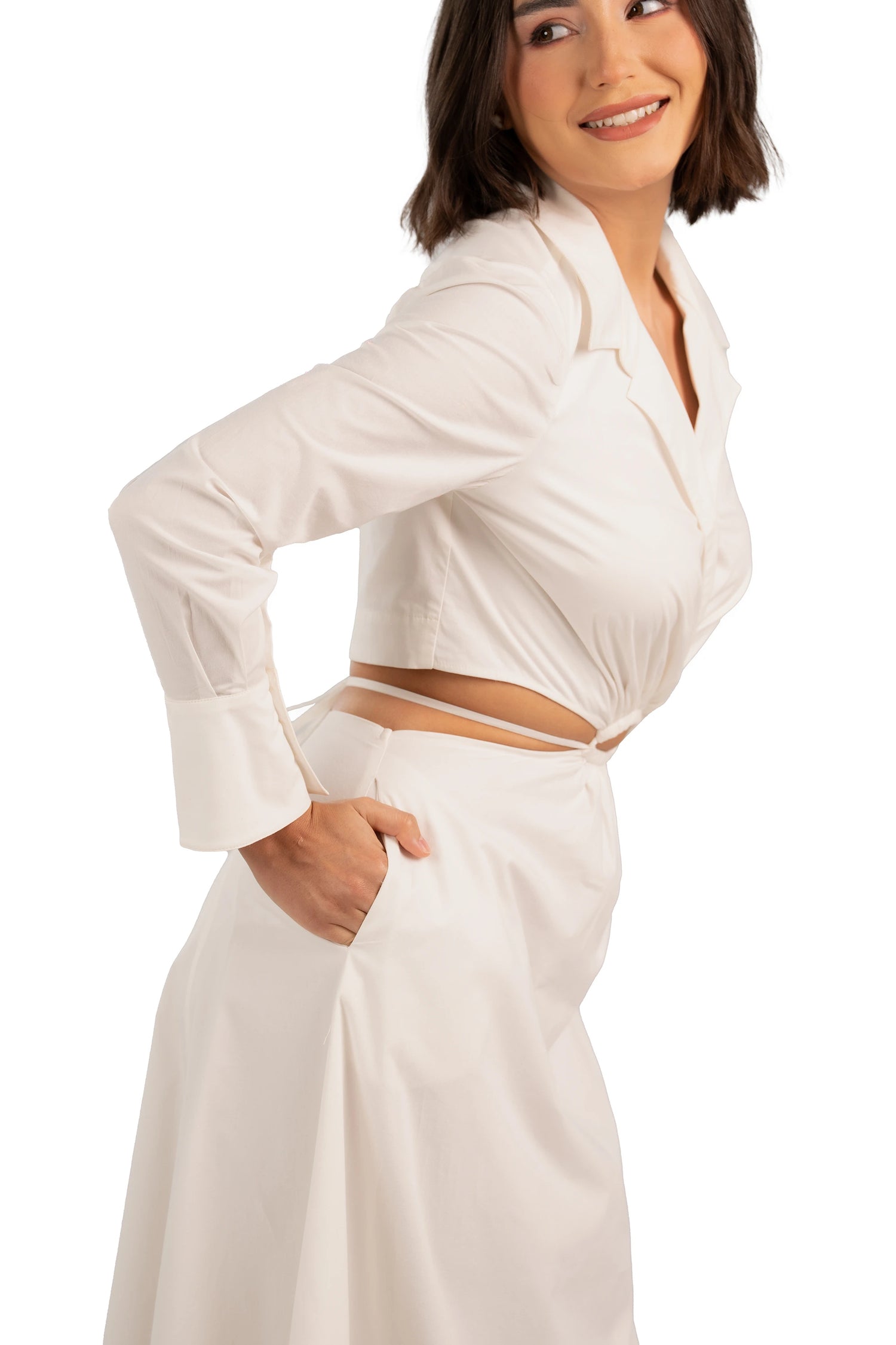 Close-up of ivory maxi dress with waist cutout, long sleeves, and elegant tailored details.
