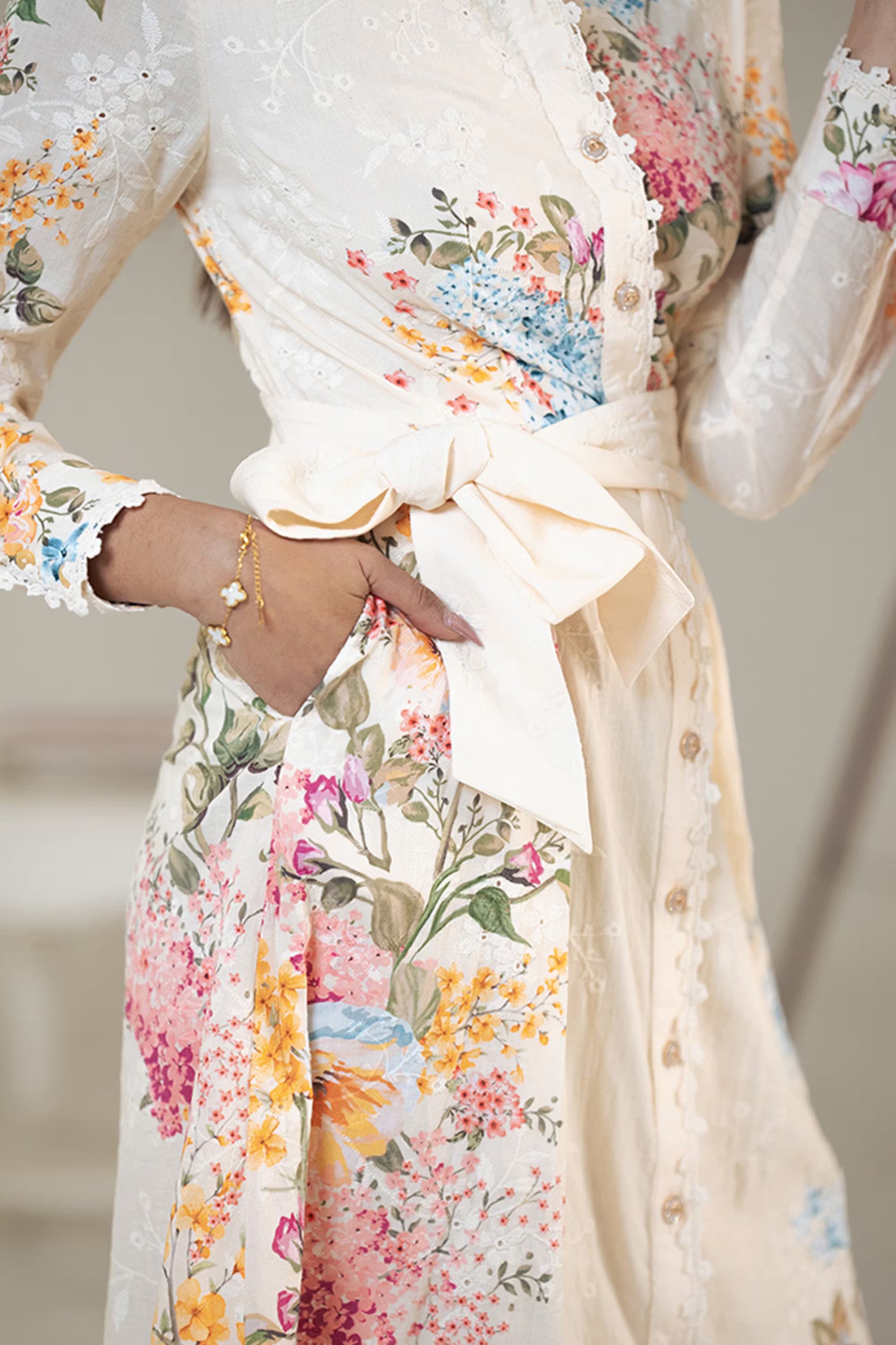 Closeup of cream floral belted shirt dress showing bow belt and floral embroidery detail