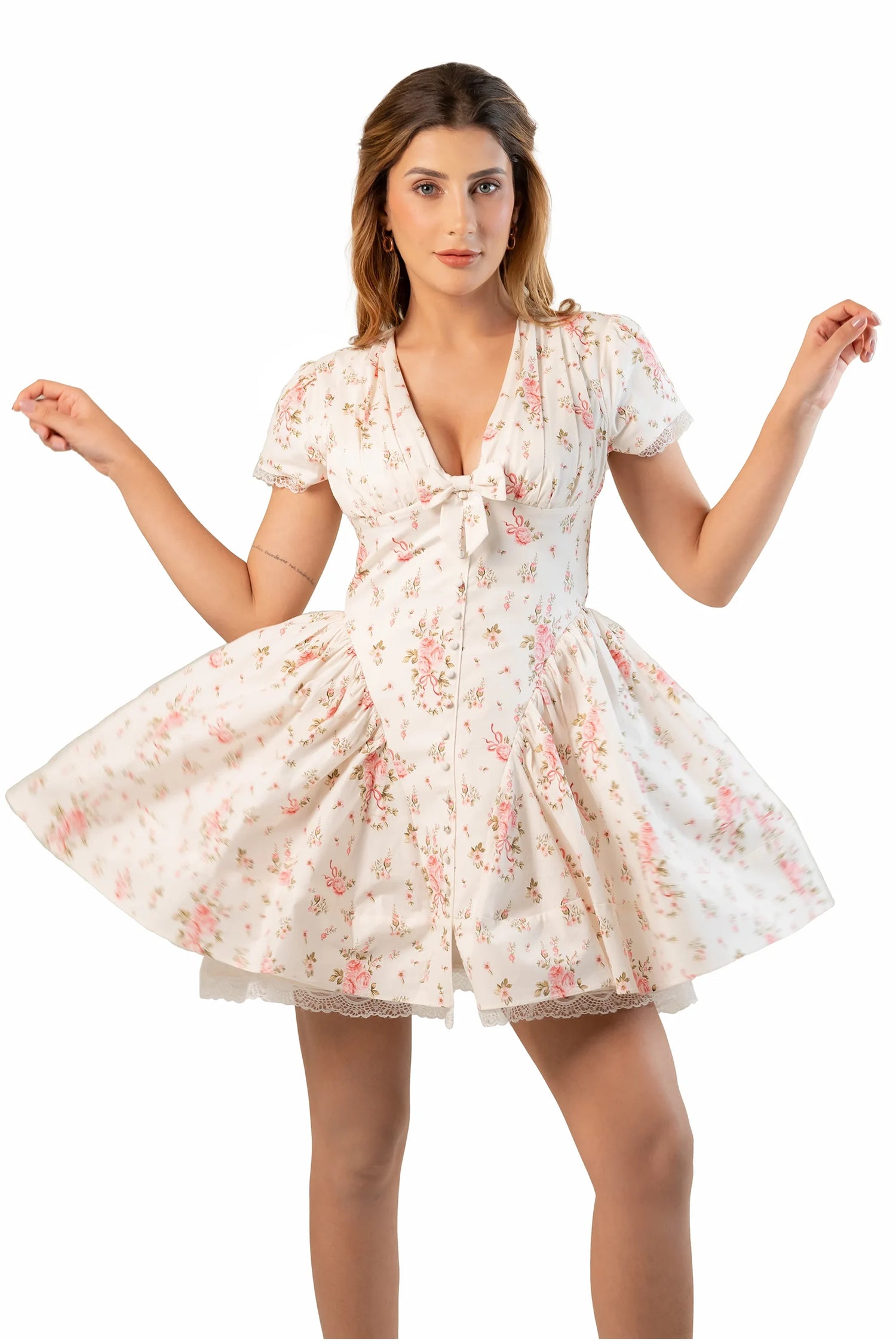 Cream floral mini dress with V-neck and short sleeves as model holds skirt to show flare.