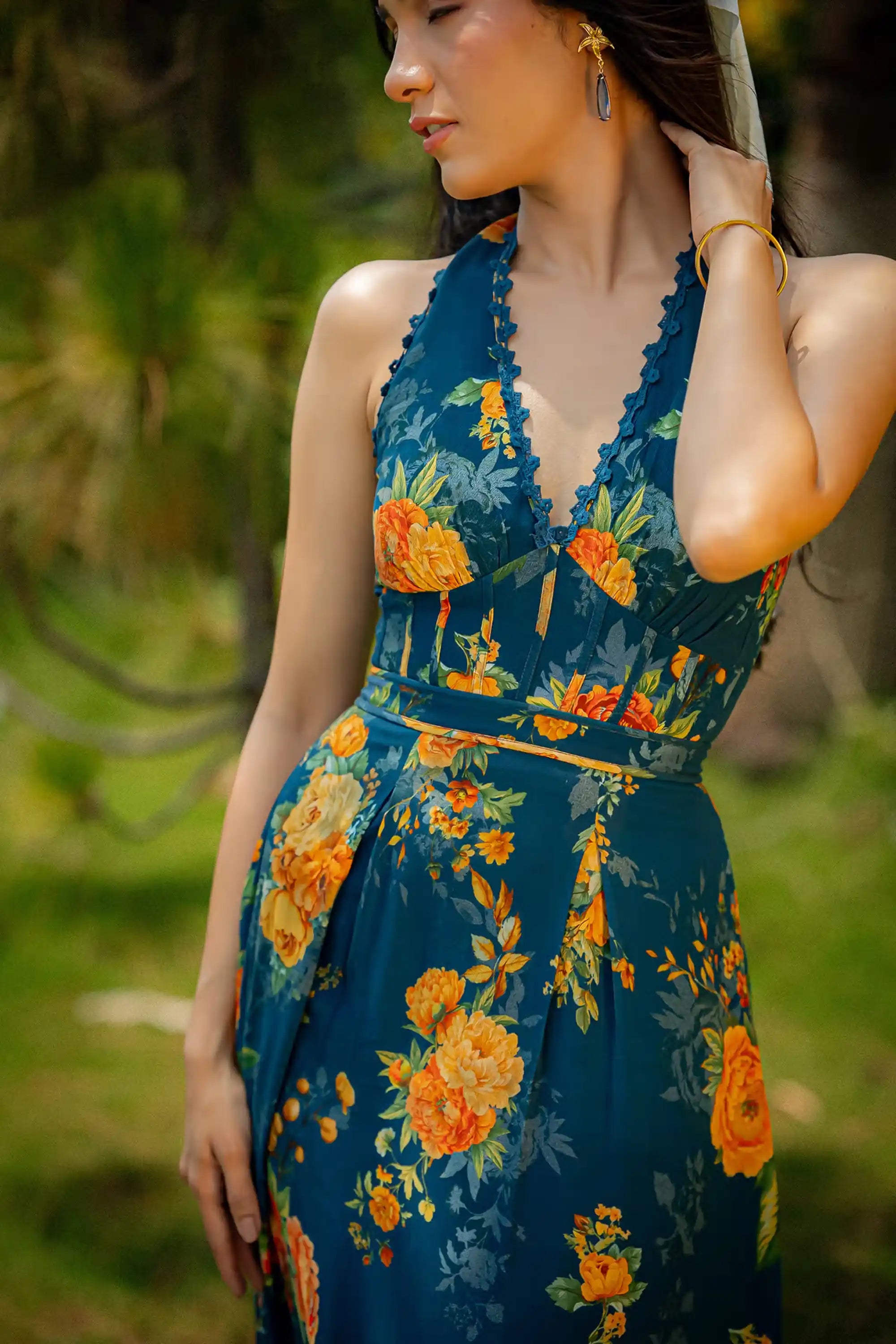 Closeup of teal halter neck maxi dress with vibrant orange-yellow floral print