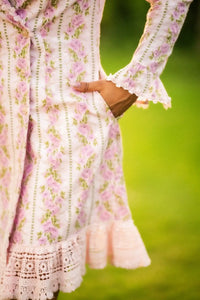 Button close-up on pink floral white lace trim mini dress