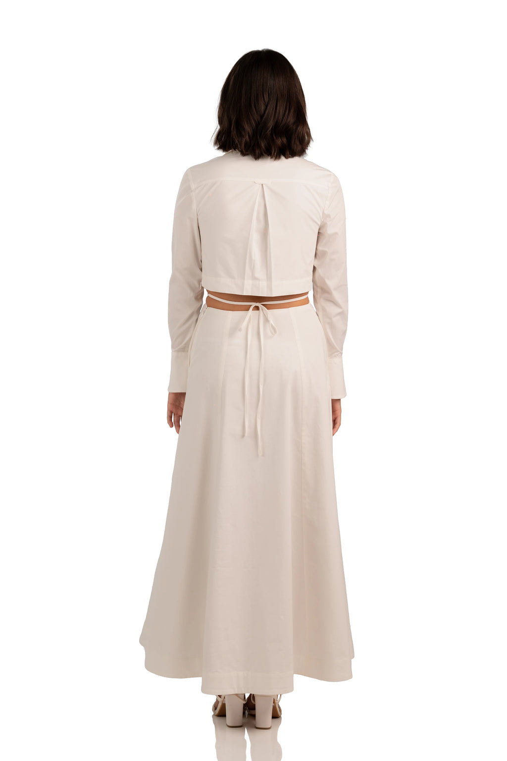 Back view of ivory maxi dress with long sleeves, tie-back detail, and waist cutout design.