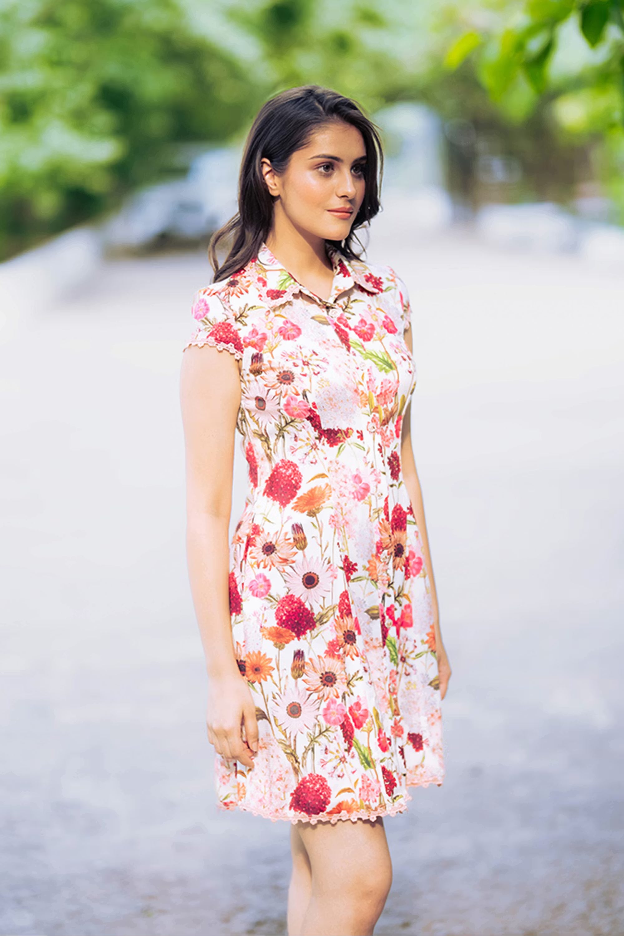 Side profile of white floral sleeveless shirt dress with lace hem and button-front style