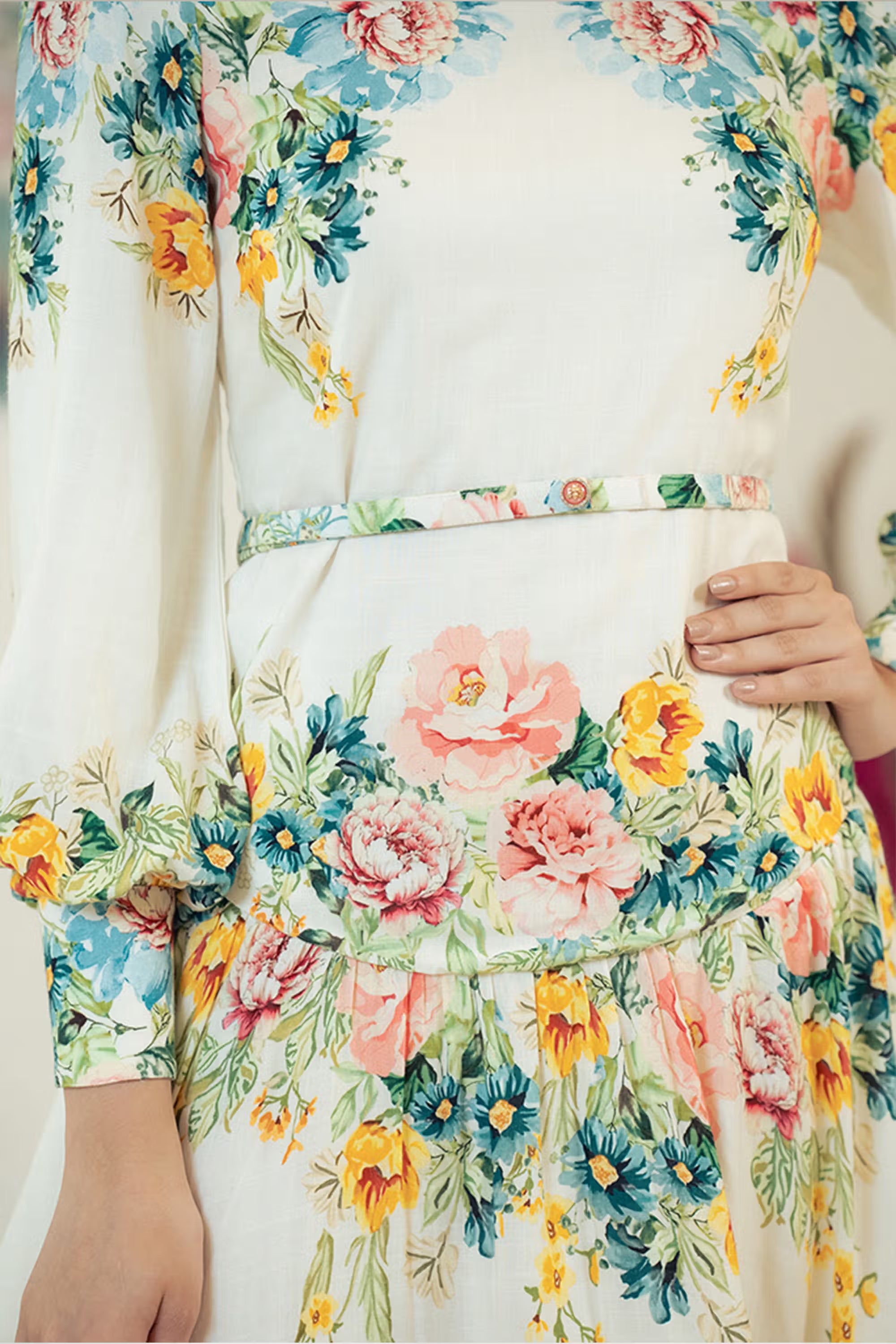 Close-up of ivory floral mini dress showing waist belt and sleeve floral print.