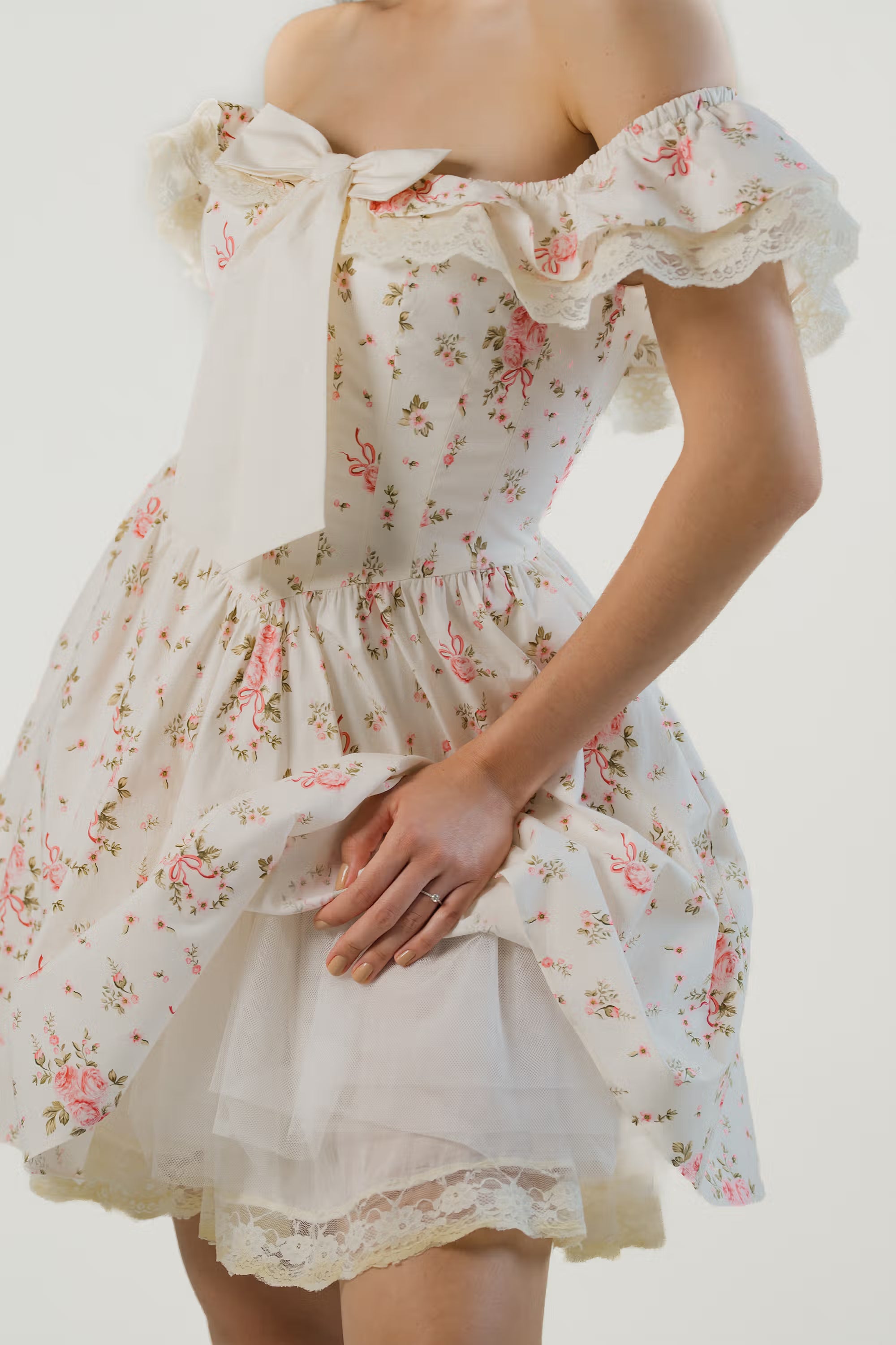 Close-up of ivory floral off-shoulder mini dress showing lace trim and oversized bow.