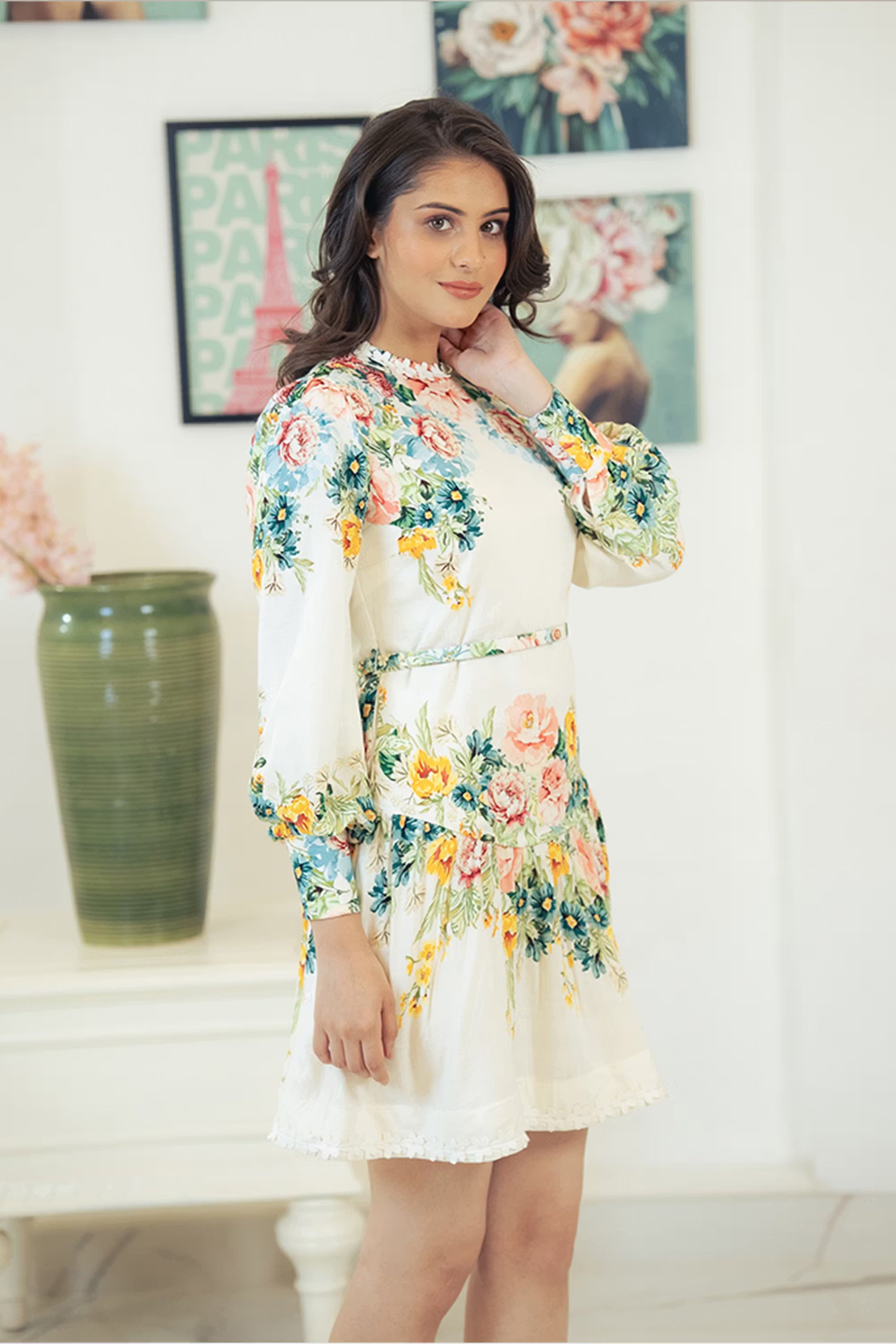 Side profile of woman in ivory long sleeve mini dress with floral print.