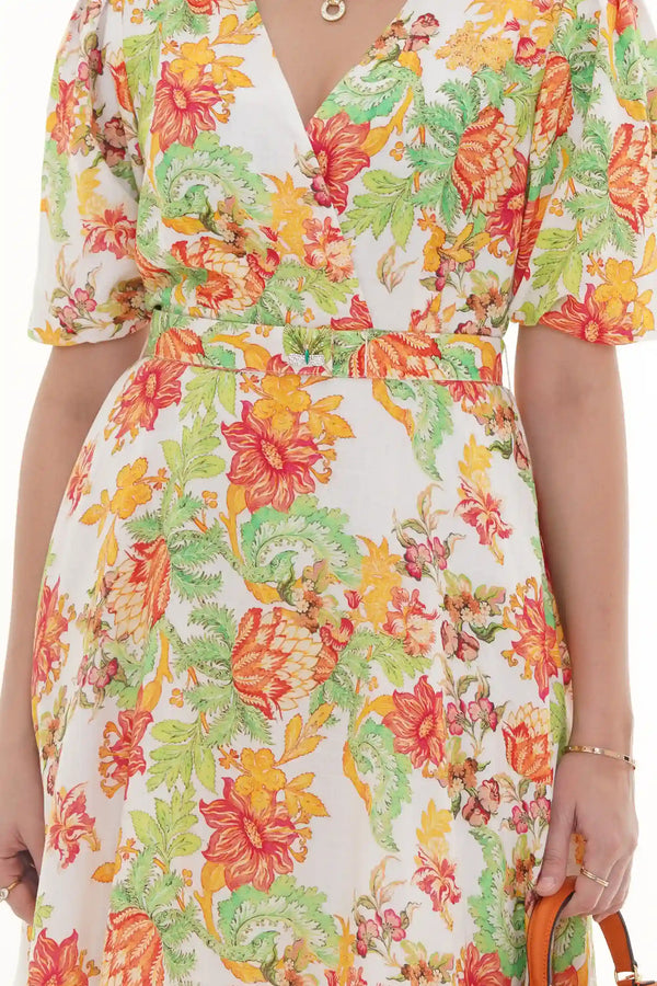 Woman in Pretty Pixie ivory tropical floral V-neck wrap dress with butterfly brooch belt