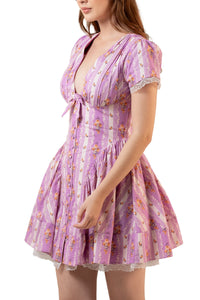 Side three-quarter view: lavender floral tie-front mini frock with puff sleeves and gathered fit-and-flare skirt