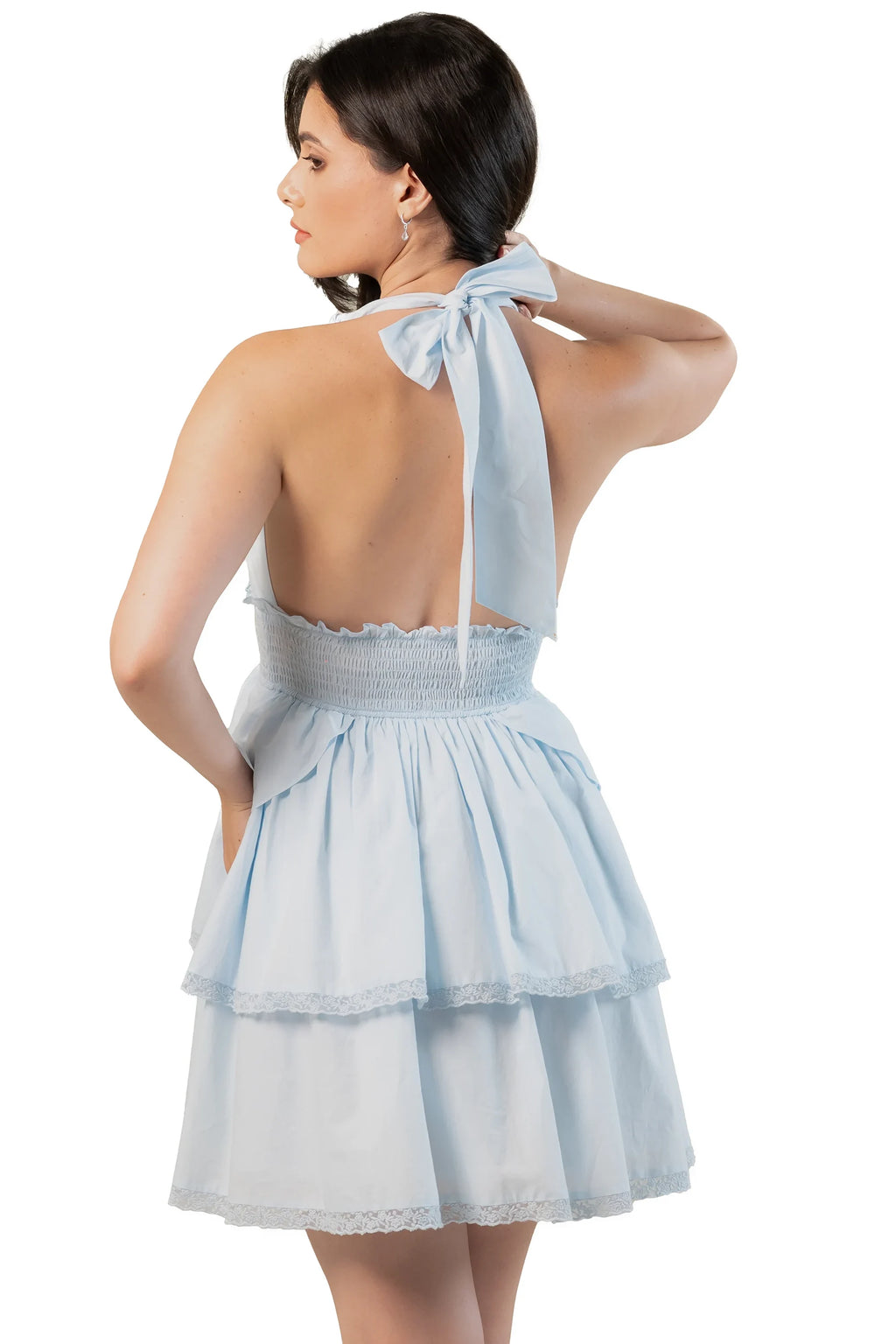 Back view of light blue tiered halter mini dress with bow tie at the neck, open back, and tiered skirt.