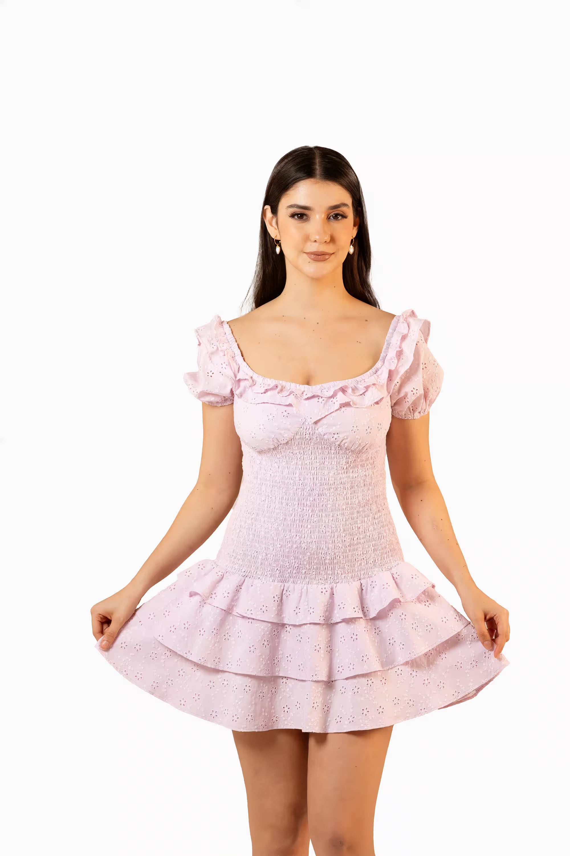 Flared light pink mini dress with ruffle details and puff sleeves, front view of model holding skirt.
