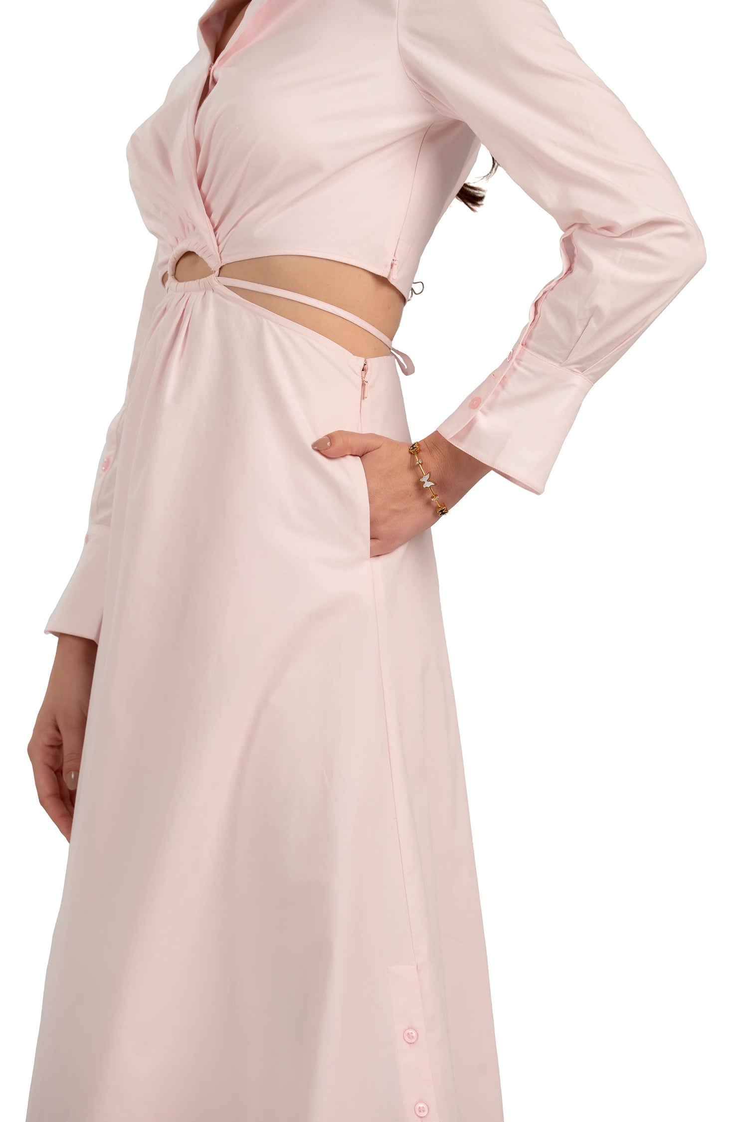Close-up of blush pink maxi dress showing waist cutout, long sleeves, and elegant tailored details.