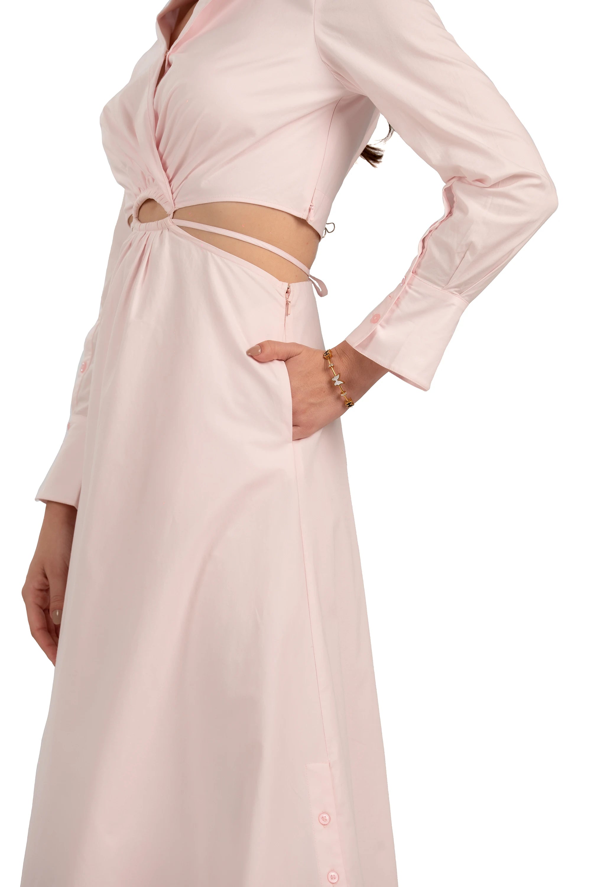 Close-up of blush pink maxi dress showing waist cutout, long sleeves, and elegant tailored details.