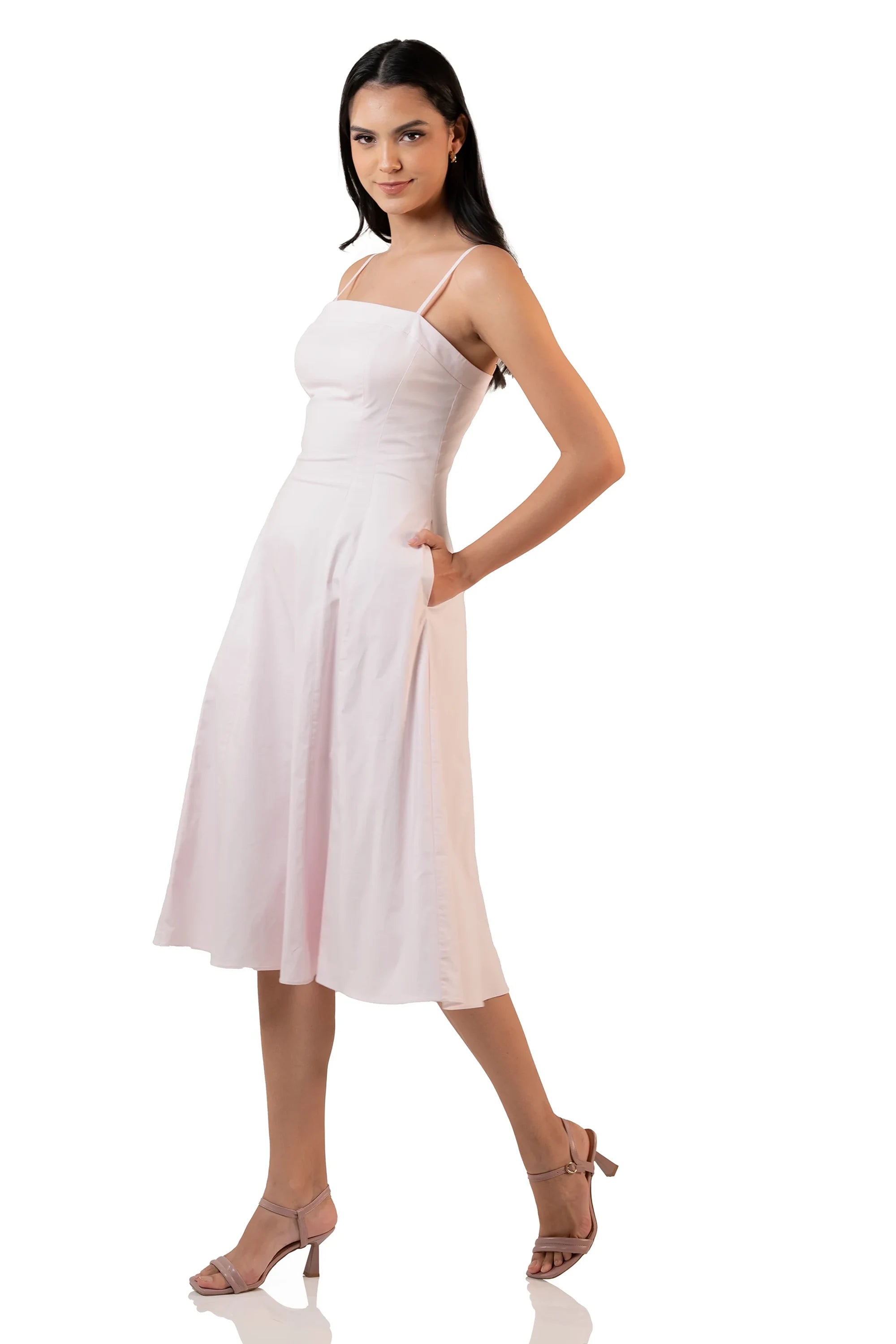 Model walking in a light pink sleeveless midi dress with spaghetti straps, showcasing movement and flow of the A-line skirt.