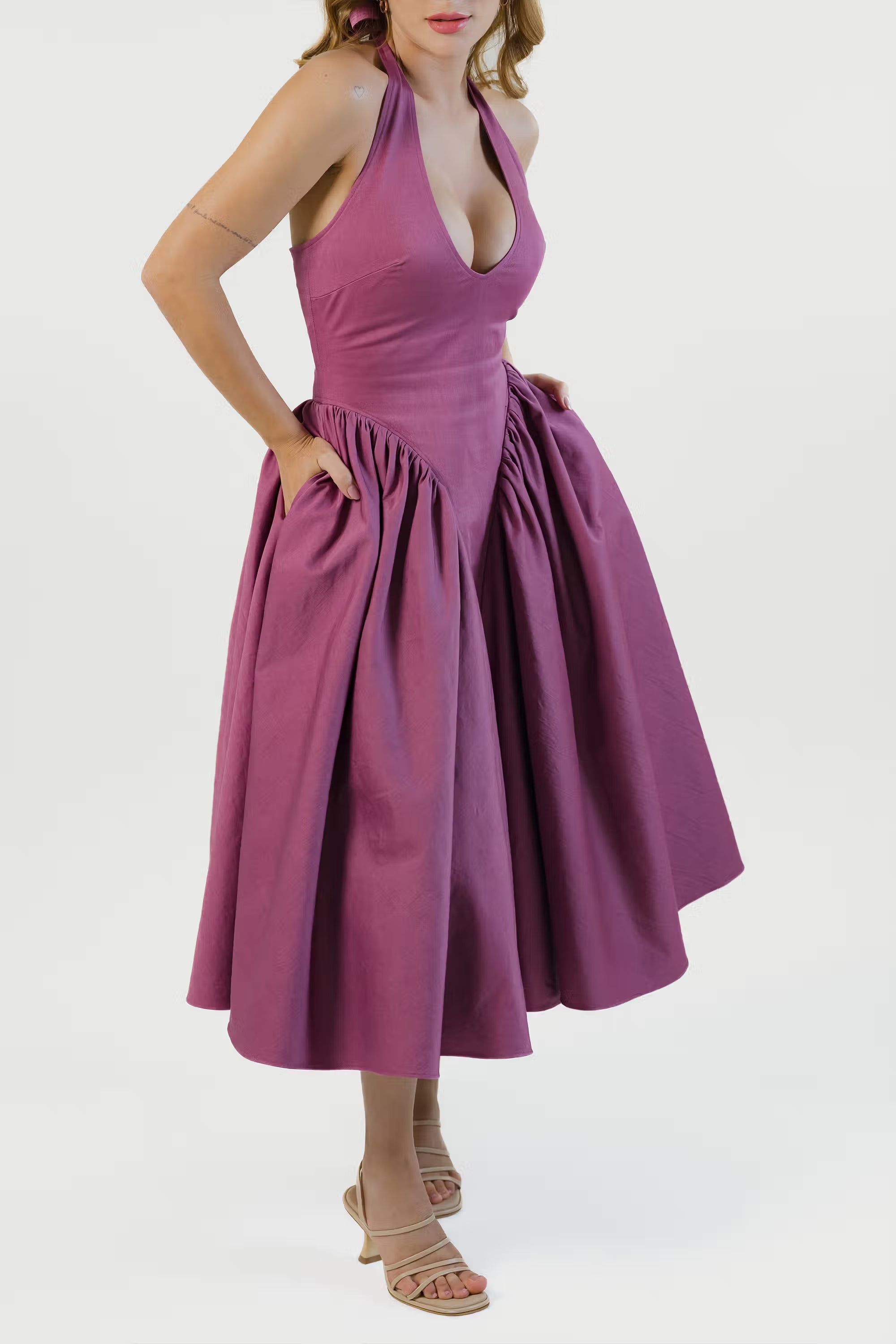 Side view of plum halter midi dress with hidden pockets and flowy pleats.