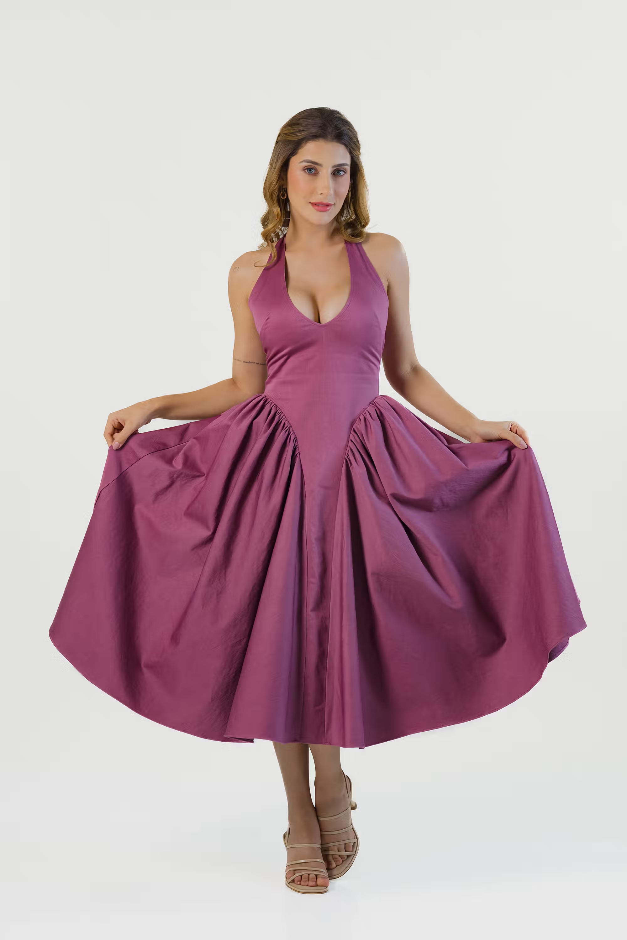 Plum halter midi dress with wide flared skirt held out, showing flowy style.