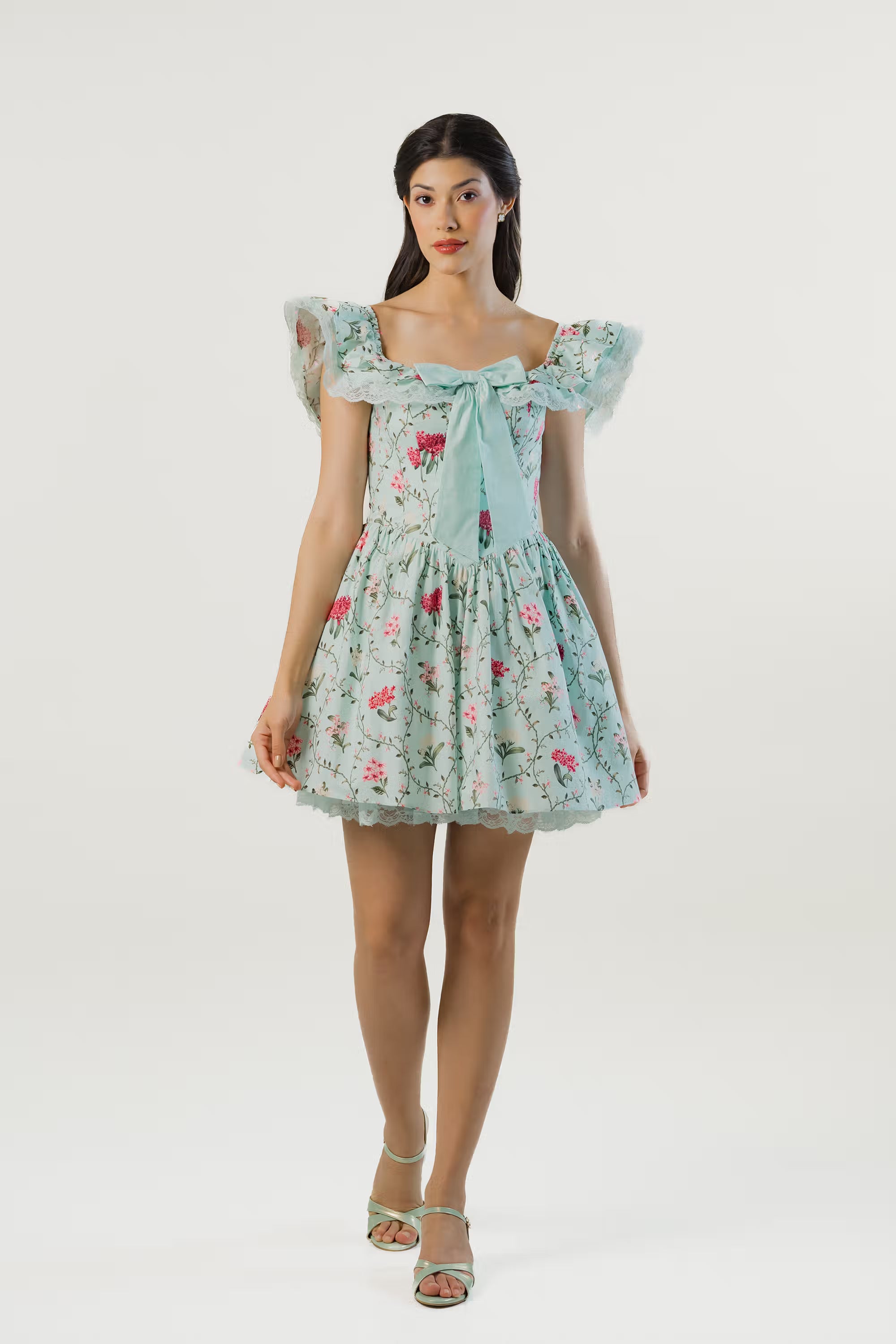 Front-facing shot of mint green off-shoulder floral short dress with feminine bow tie detail.