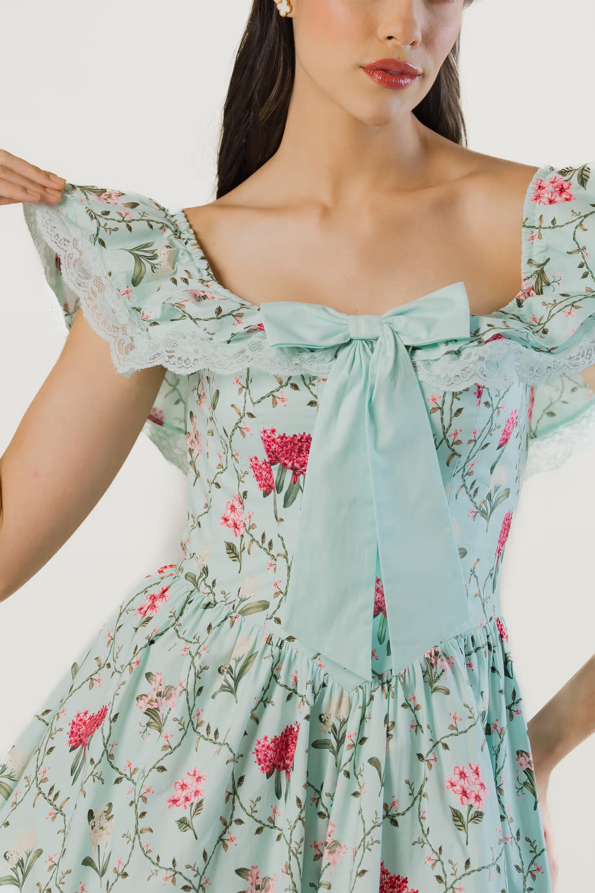 Close-up of bow tie and lace trim on mint green floral off-shoulder short dress.