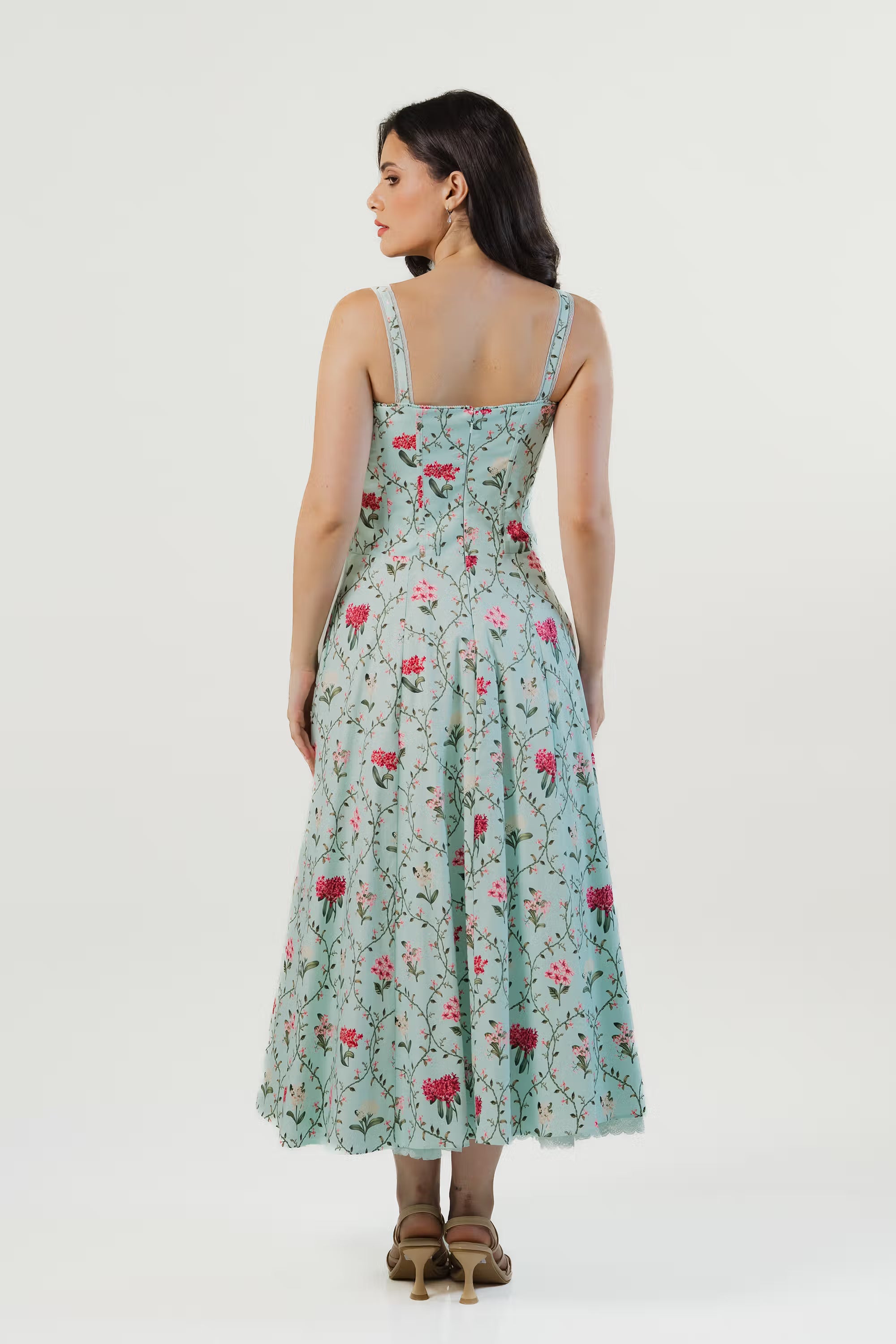 Back view of mint green floral maxi dress with corset paneling, sleeveless straps, and red blossom print.