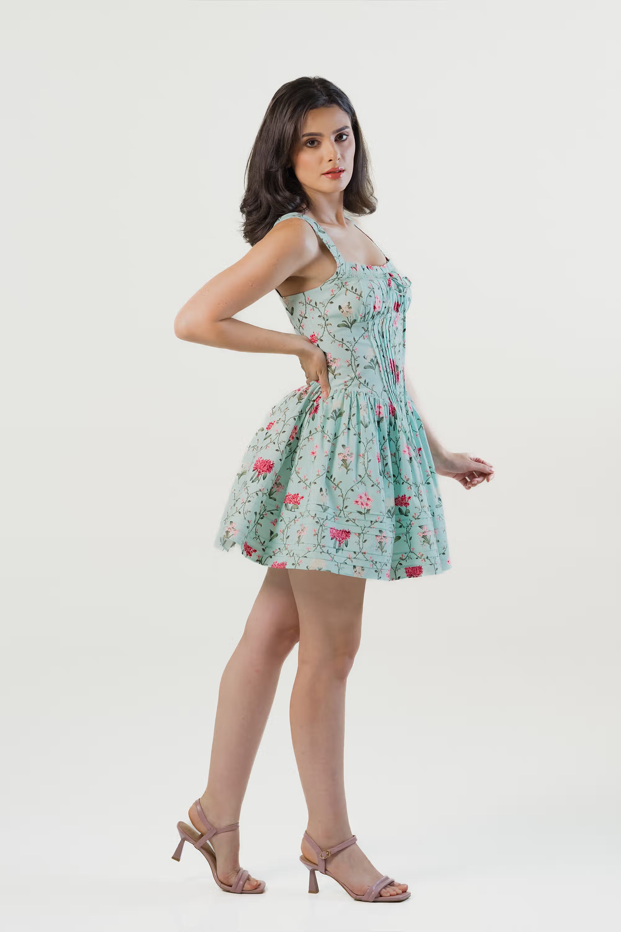 Hemline detail of mint green mini dress with pink floral print and pleats